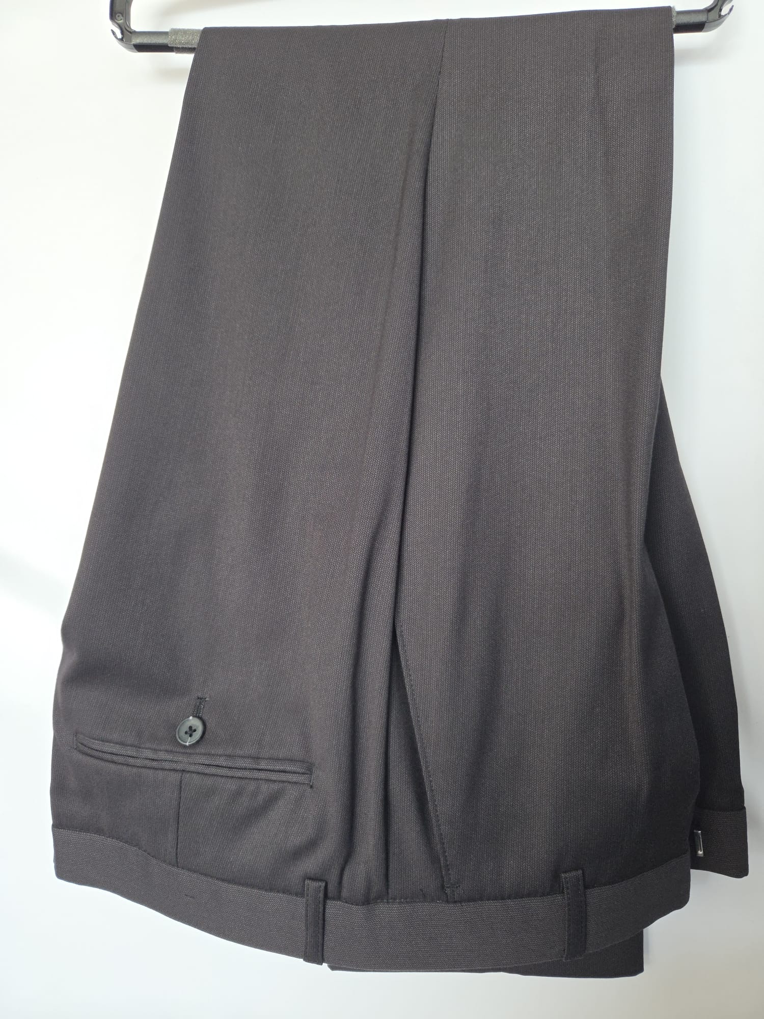 Close-up of matching black trousers with rear pocket and button.