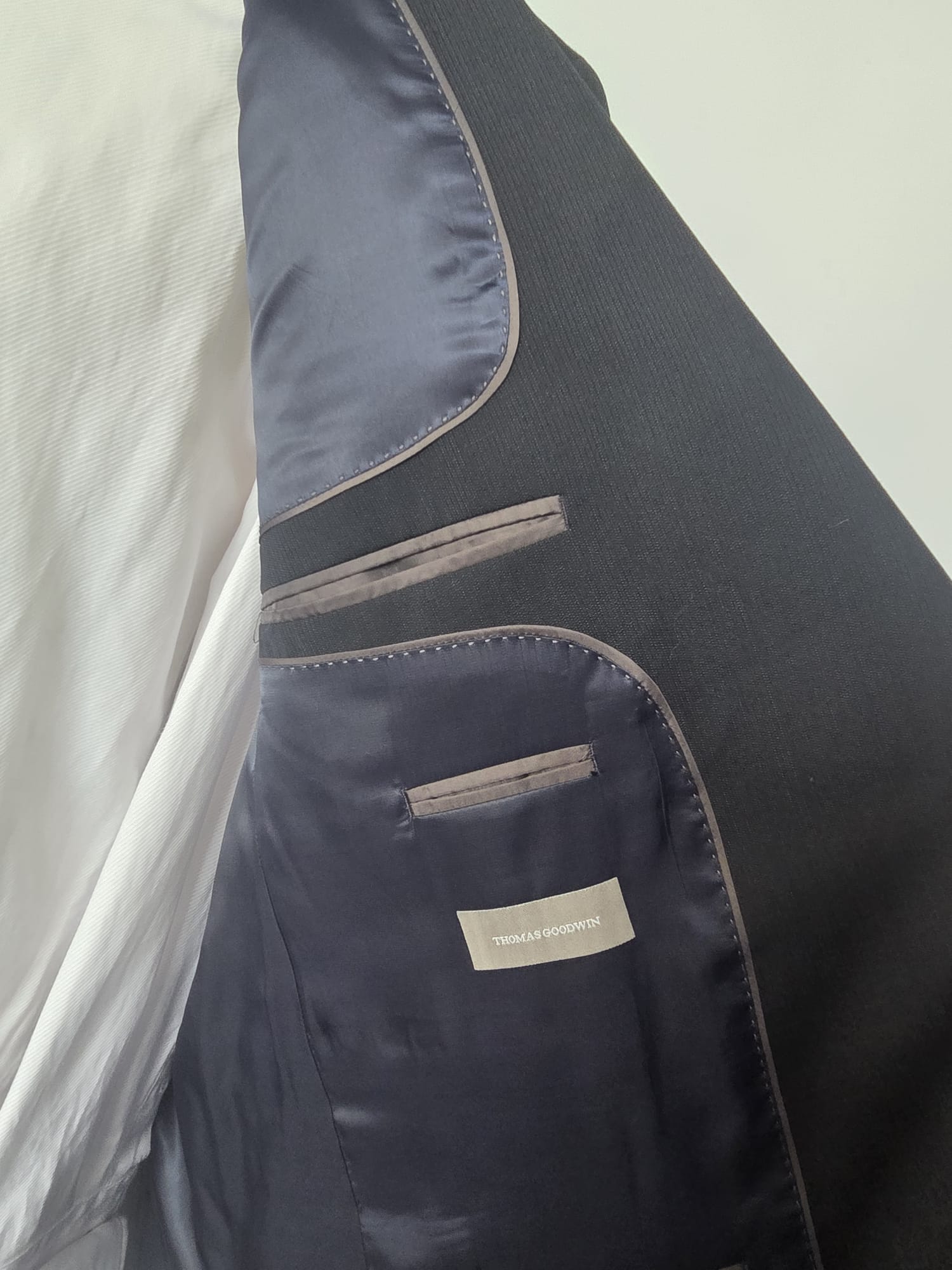 Inside lining of dark navy Thomas Goodwin suit showing brand label and internal pockets.