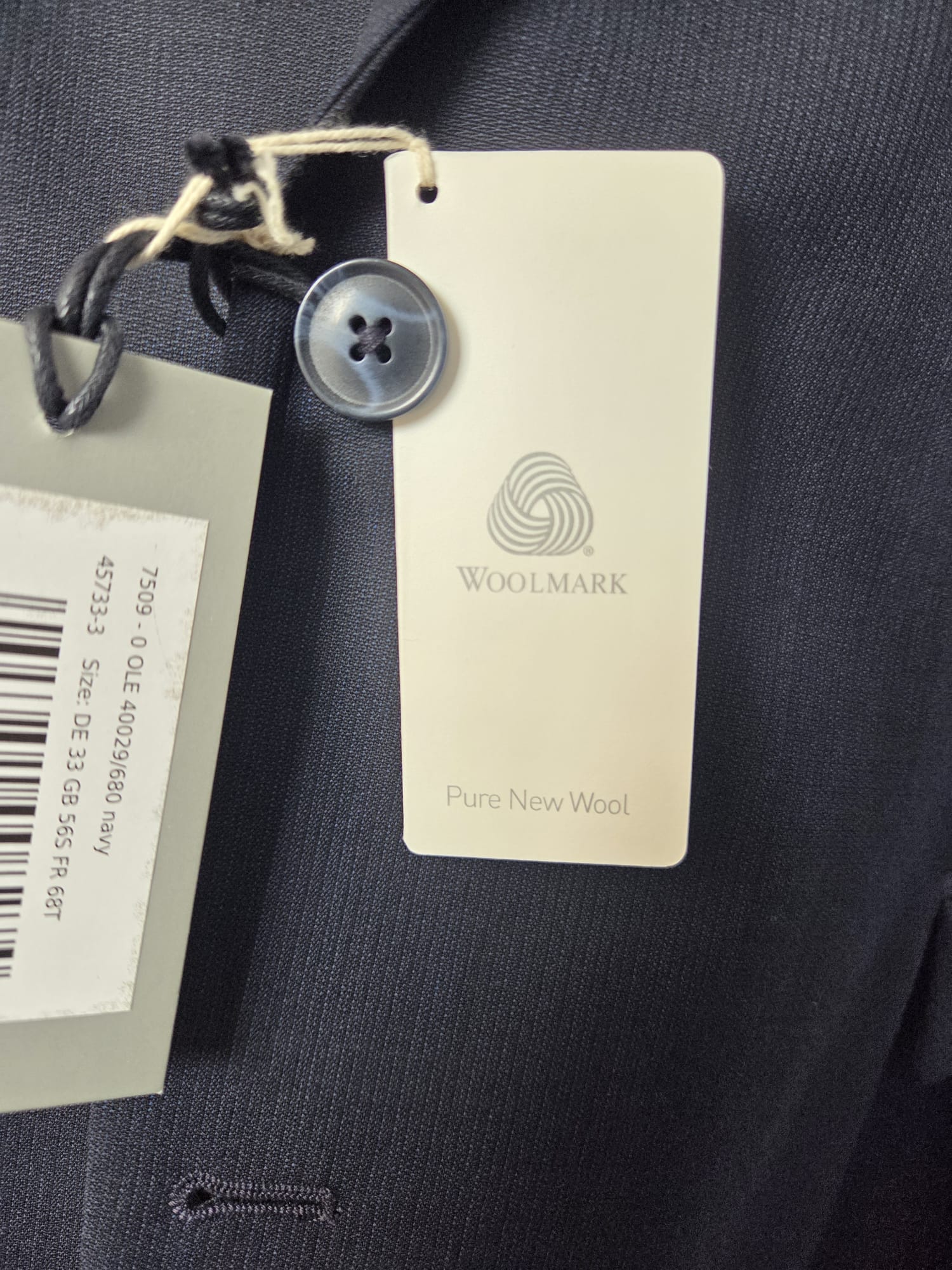 Woolmark Pure New Wool tag on dark navy Thomas Goodwin suit fabric indicating 100% virgin wool.