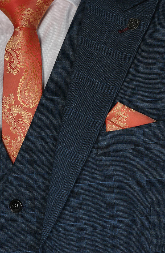 Close-up of the lapel, showing the navy check texture with a vibrant orange paisley tie and matching pocket square.