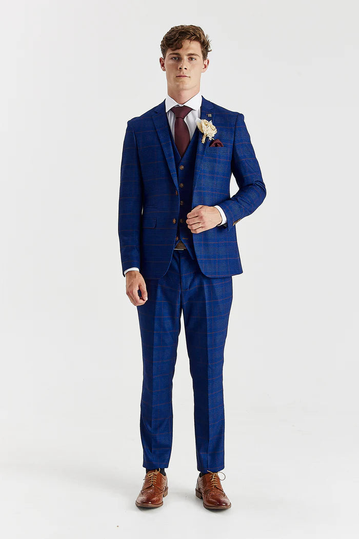 Full-length view of Alex navy burgundy check three piece suit with blazer, waistcoat, and trousers and wearing brown brogues. 