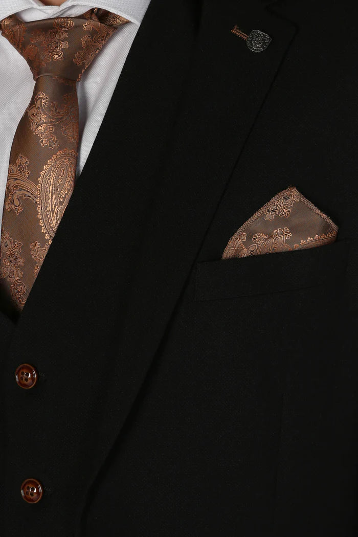 Close-up of lapel and chest pocket of black suit with copper paisley tie and matching pocket square.