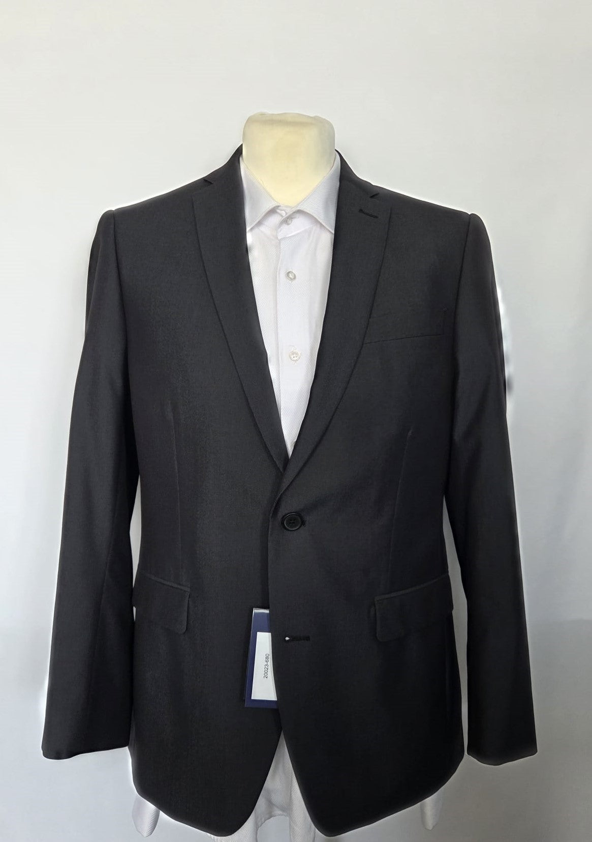 Front view of dark grey suit jacket with flap pockets and hang tag, tailored fit.