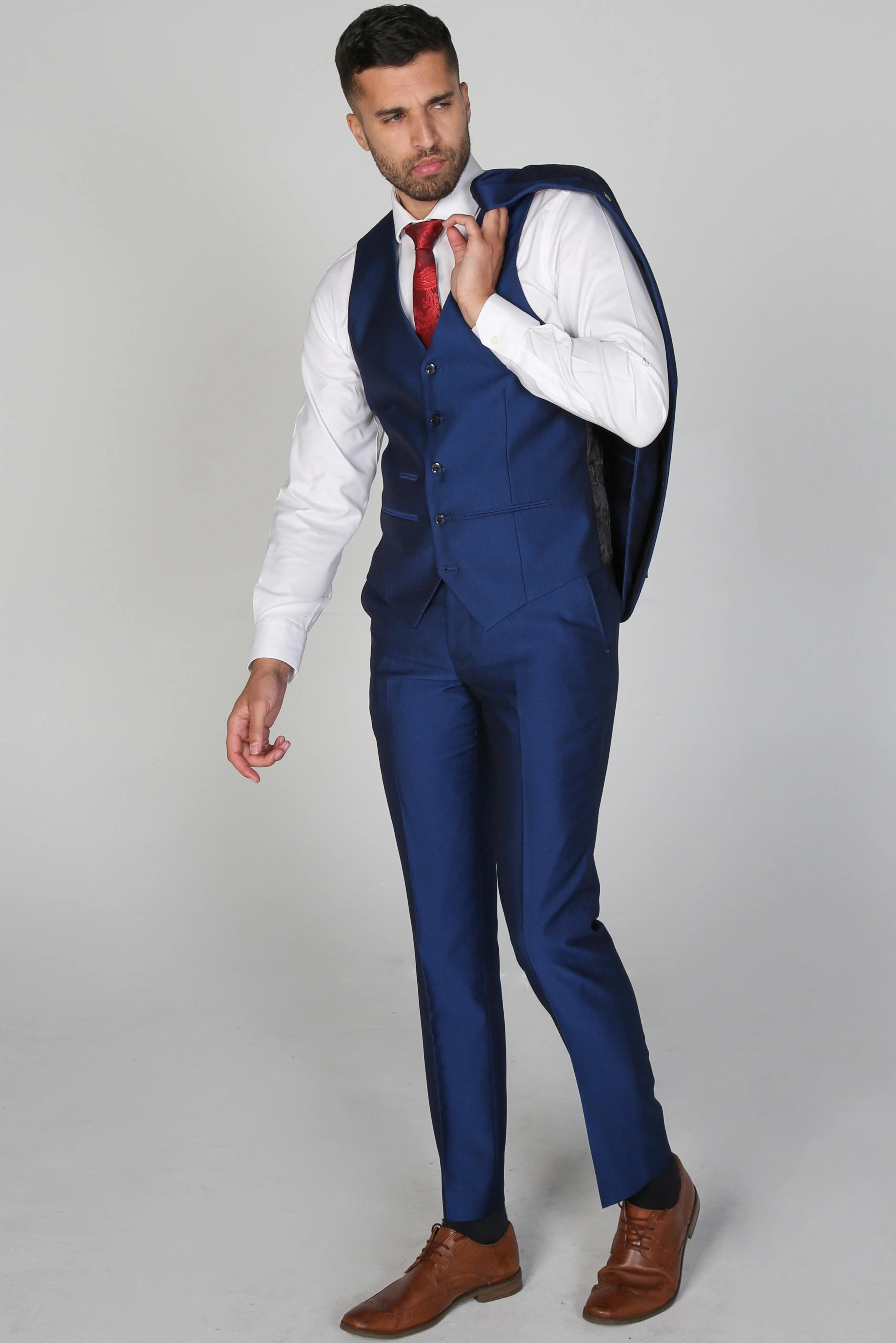 Kingsley Blue Men's three-piece suit with a white dress shirt and red tie, jacket removed and held over shoulder.
