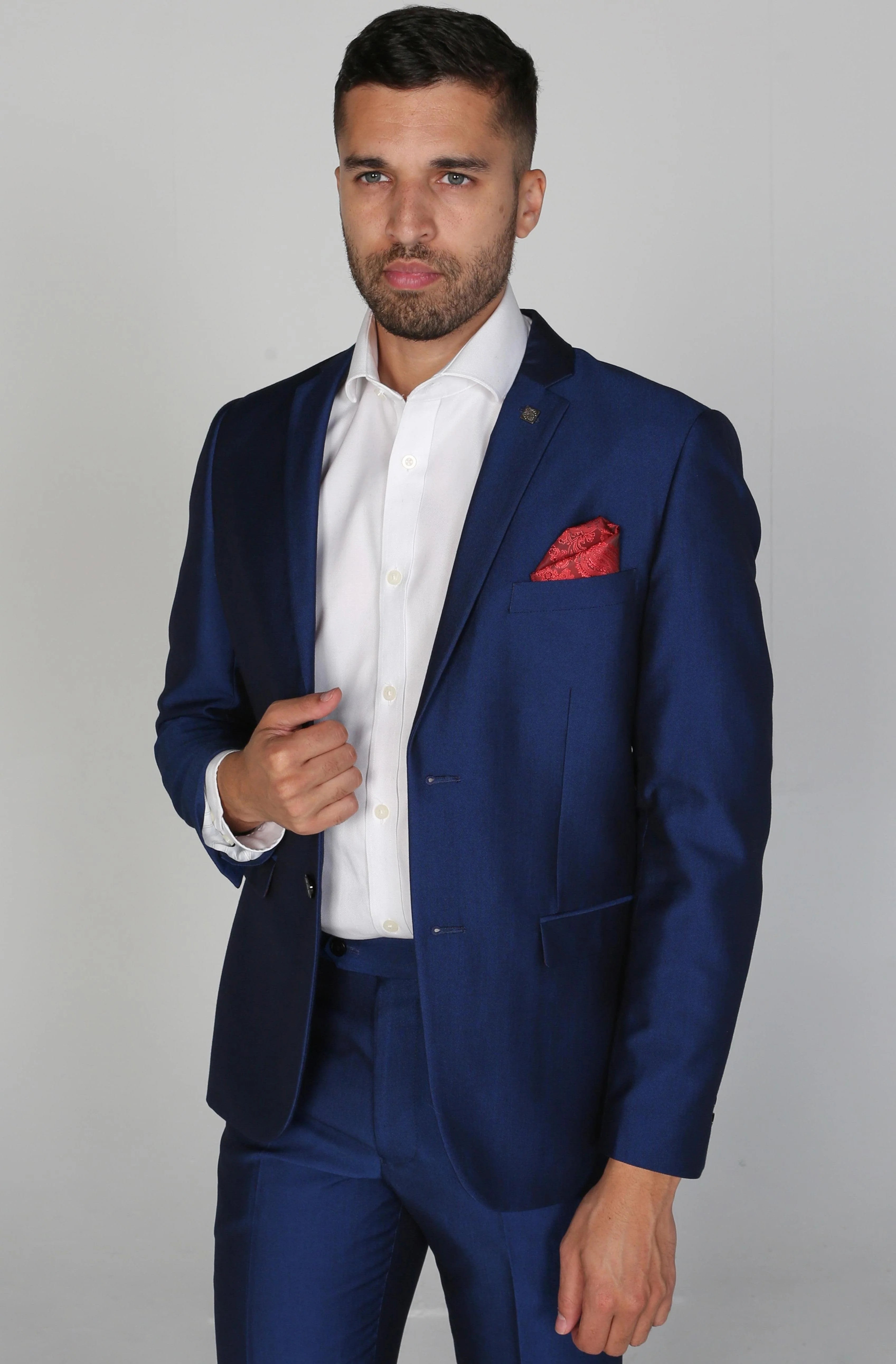 Kingsley Blue Men's three-piece suit with a white dress shirt and red pocket square, model holding lapel.