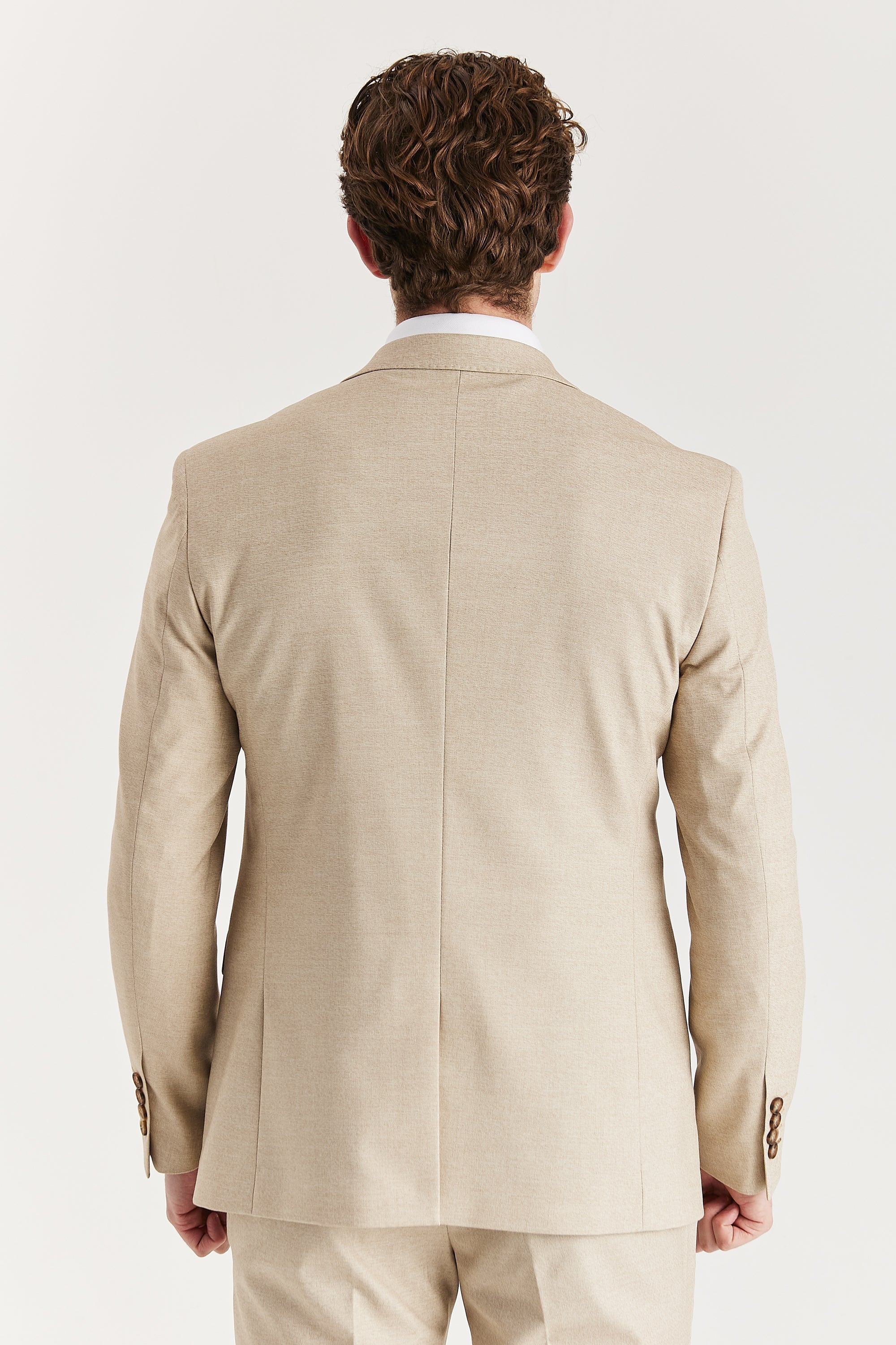 Rear view of the beige blazer and trousers, and showcasing the brown buttons on sleeve.
