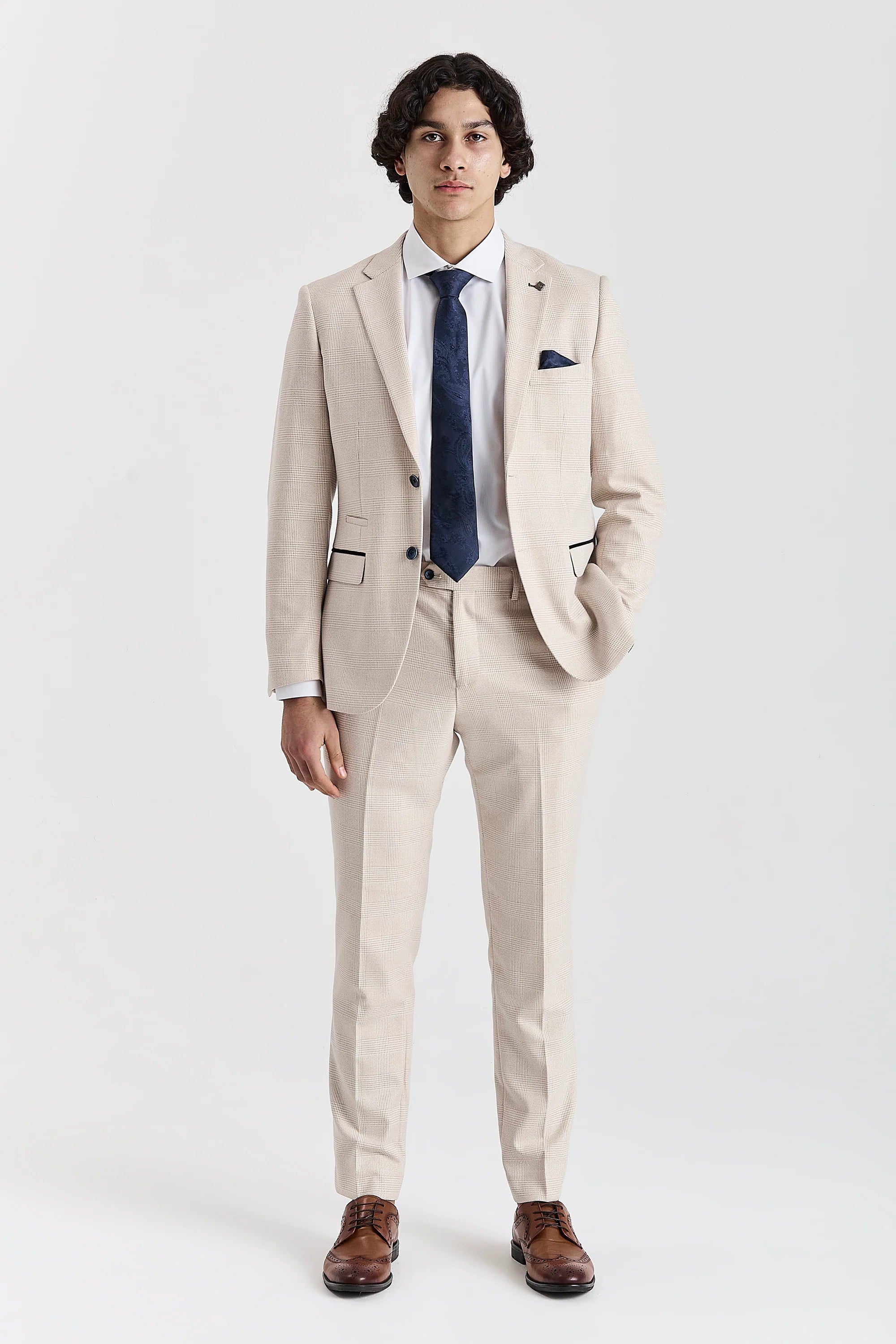 Full-length front view of the cream glen check blazer, worn with matching trousers, a white shirt, navy paisley tie, matching pocket square and brown shoes.