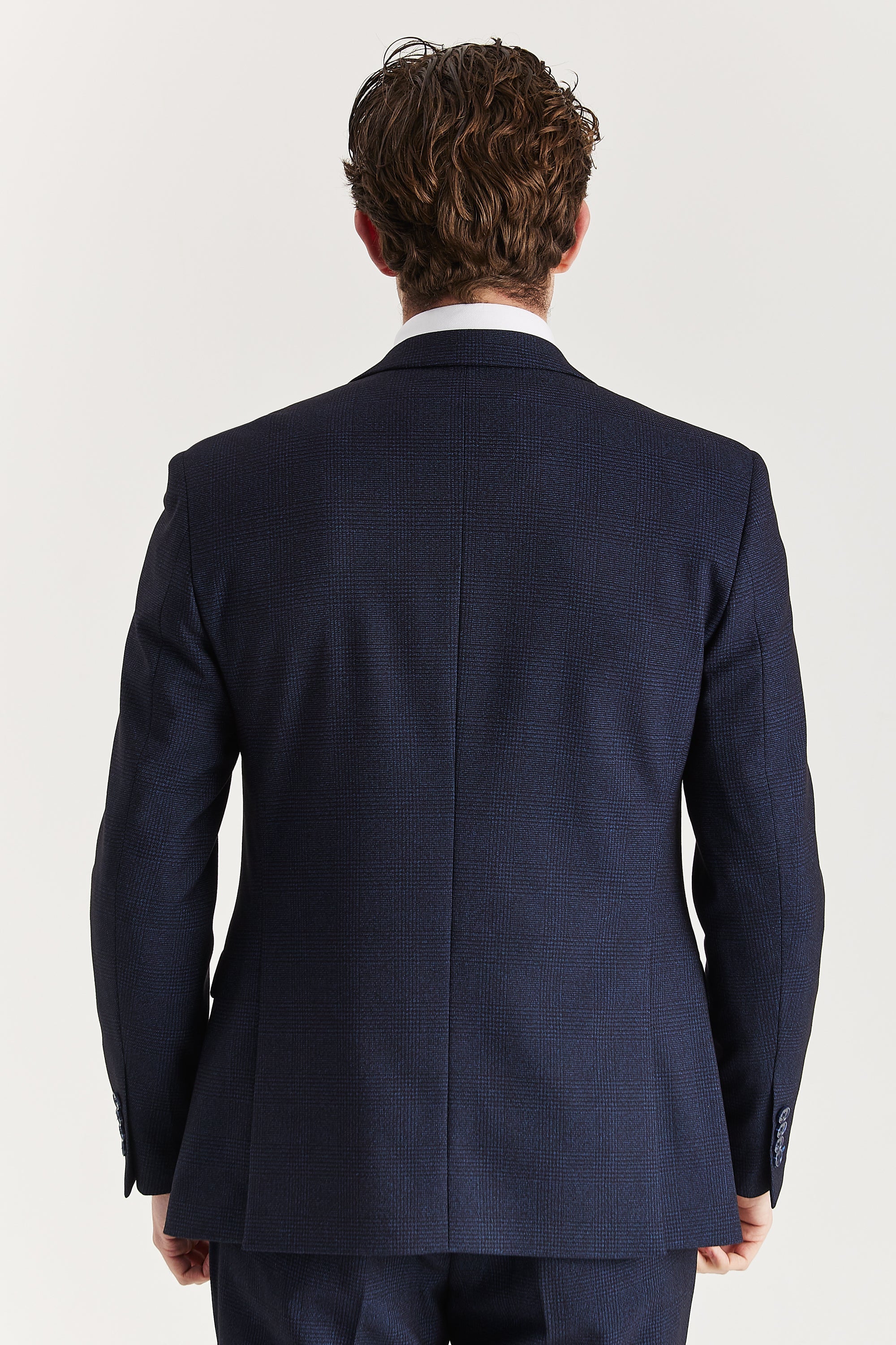 Rear view of the navy check blazer with a ventless back, central back seam and dark navy sleeve buttons.
