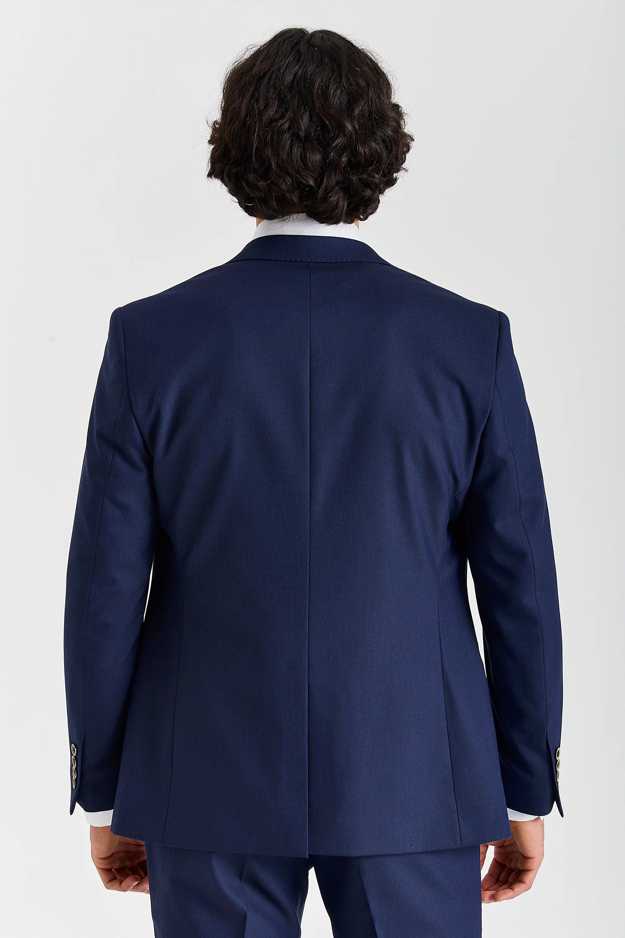 Rear view of the navy blazer with a ventless back, central back seam and sleeve buttons.