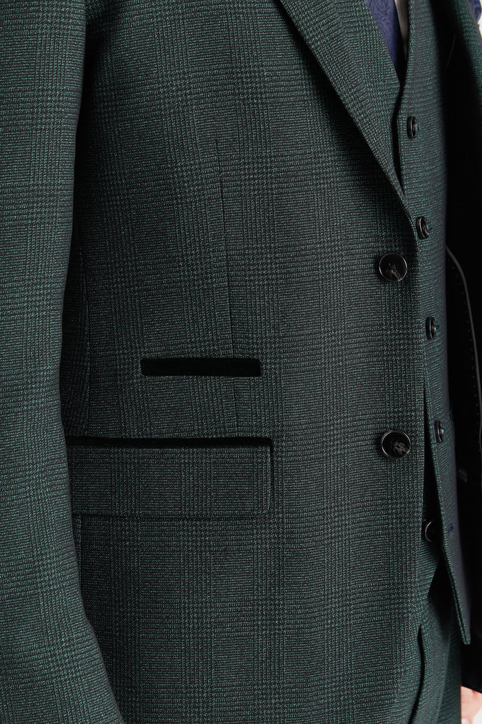 Close-up of the blazer pocket showing the olive green check fabric and contrasting dark green velvet trim.