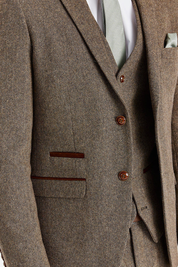 Close-up of a brown tweed suit with brown buttons and pocket details.