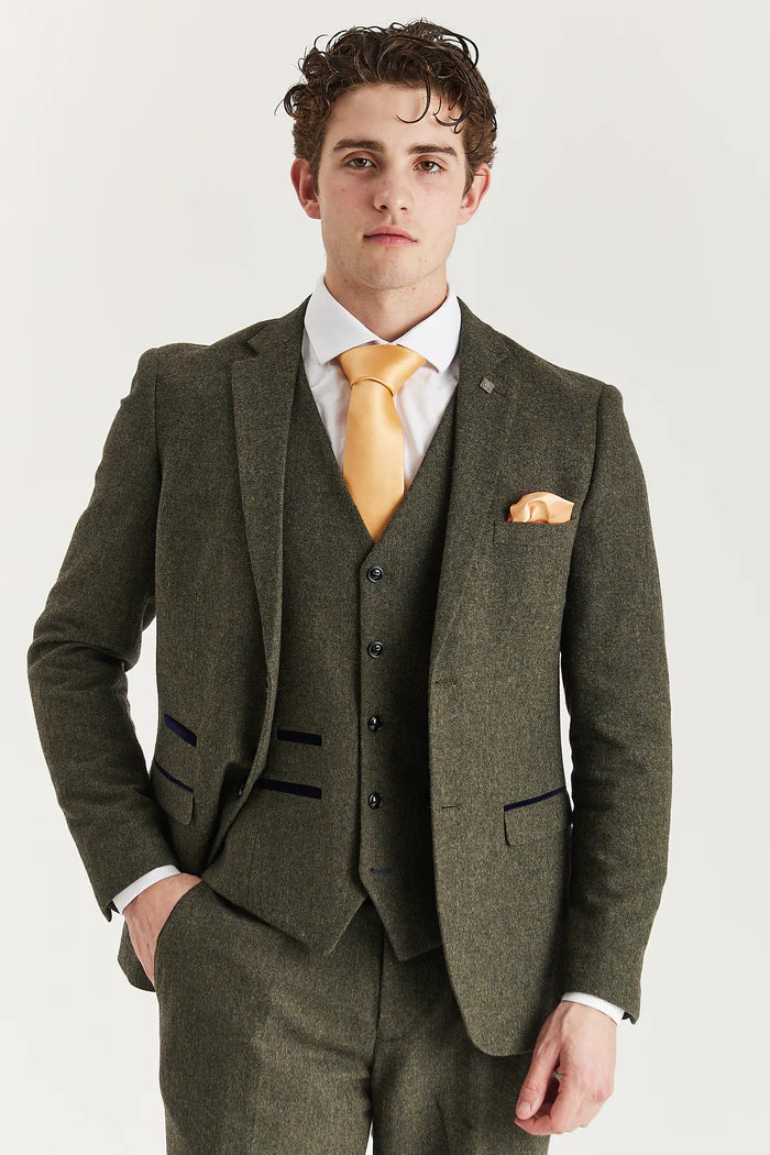 Close-up of Oscar green tweed three-piece suit jacket with matching waistcoat, white shirt, and golden-yellow tie and pocket square.