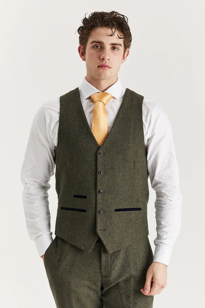 Front view of Oscar green tweed waistcoat with black buttons and dark trim, paired with white shirt and golden-yellow tie.

