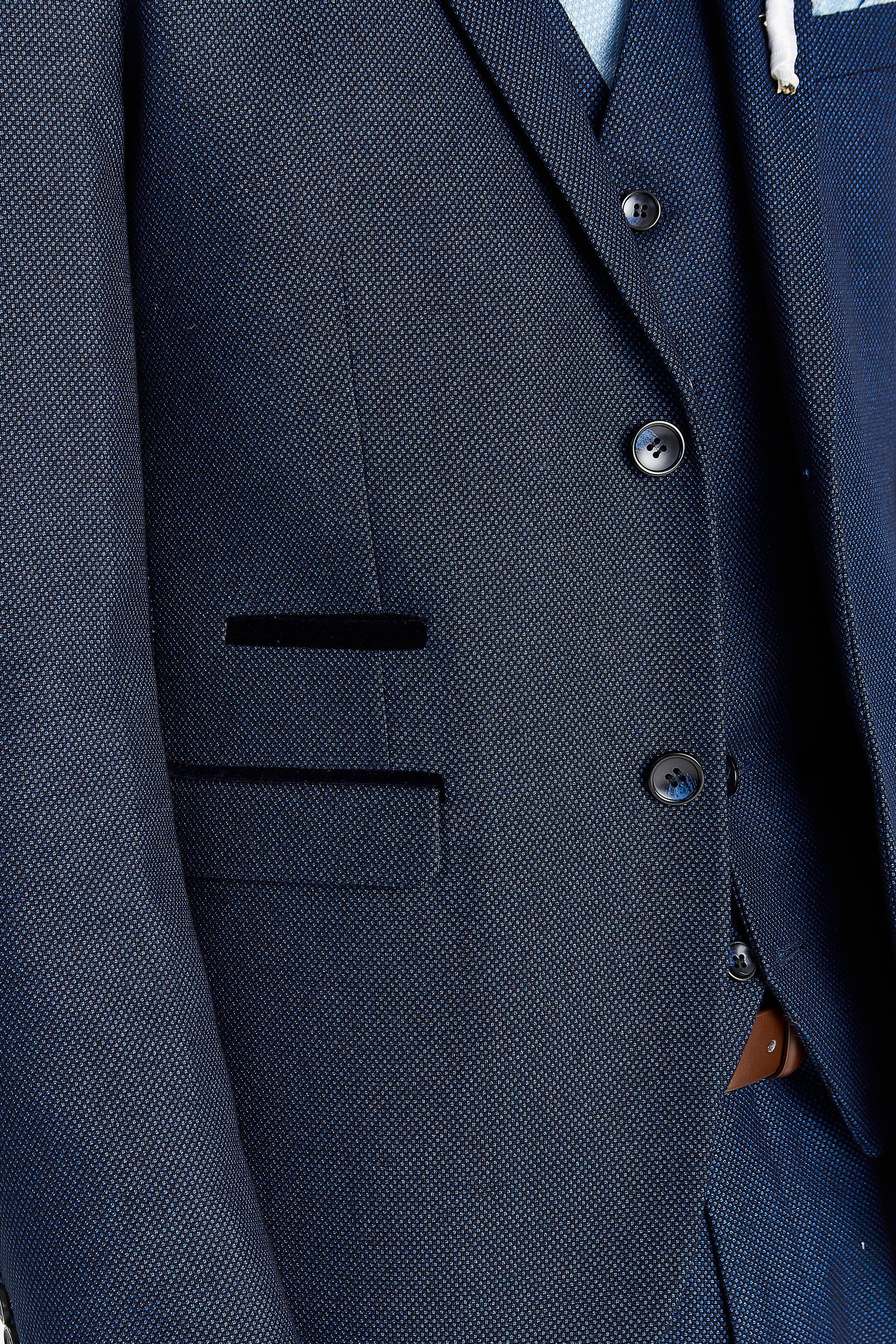 Detail view of the navy birdseye jacket and waistcoat, showing dark buttons and suede-trimmed pocket edges.