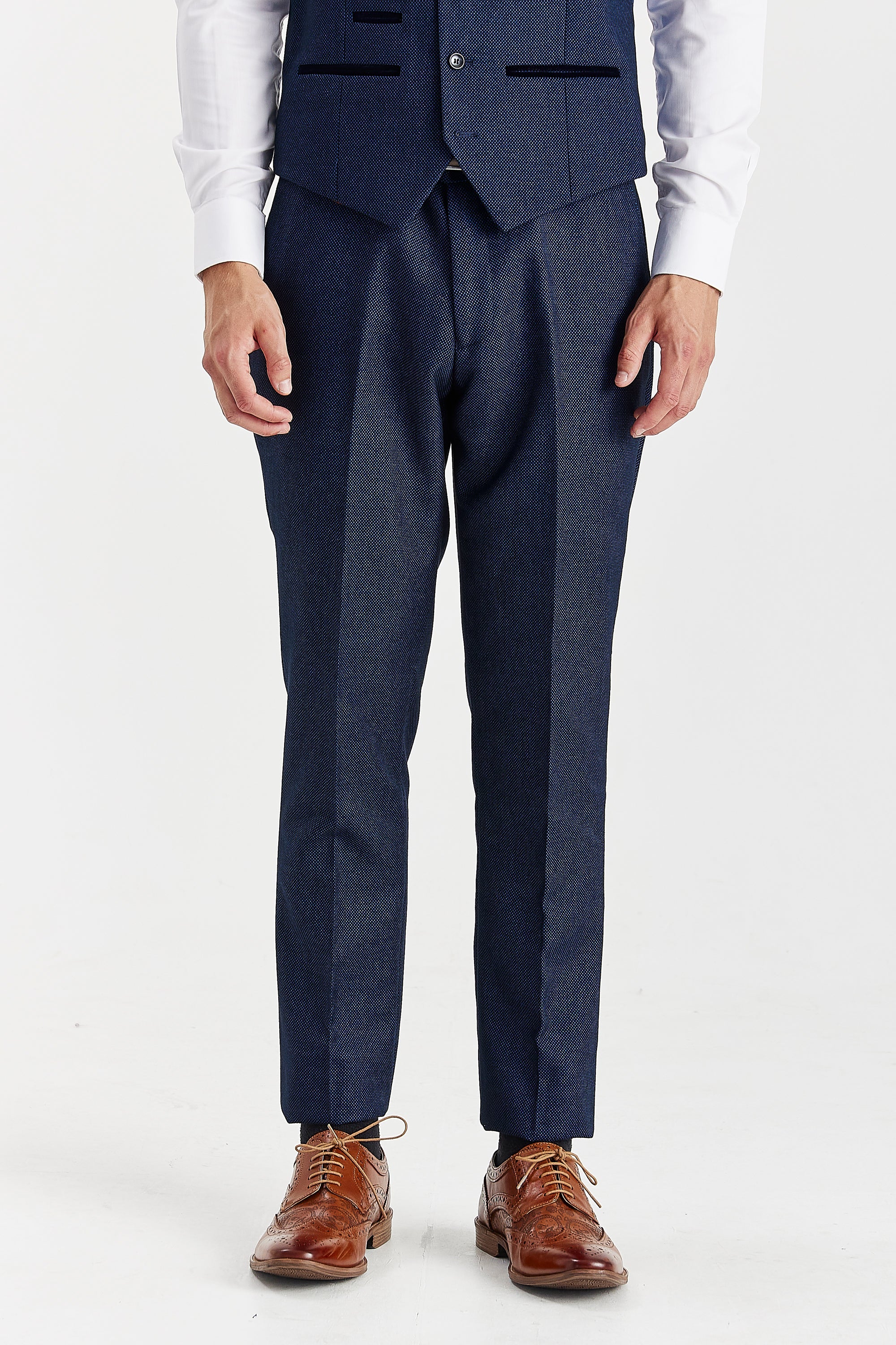 Front view of navy birdseye trousers, shown with a matching waistcoat, white shirt cuffs and brown shoes.