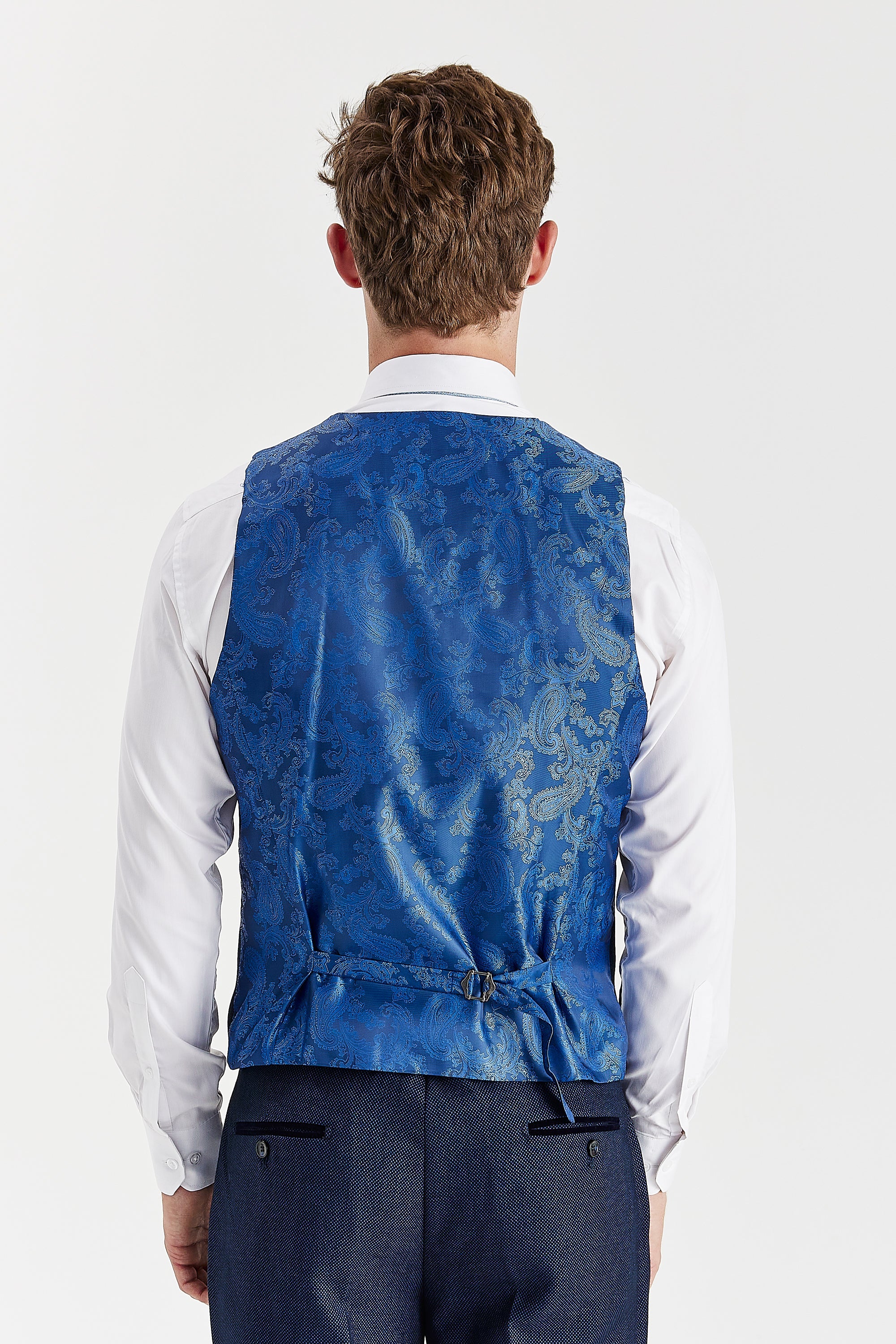 Back view of a navy waistcoat with a blue paisley satin-finish back panel and an adjustable strap.