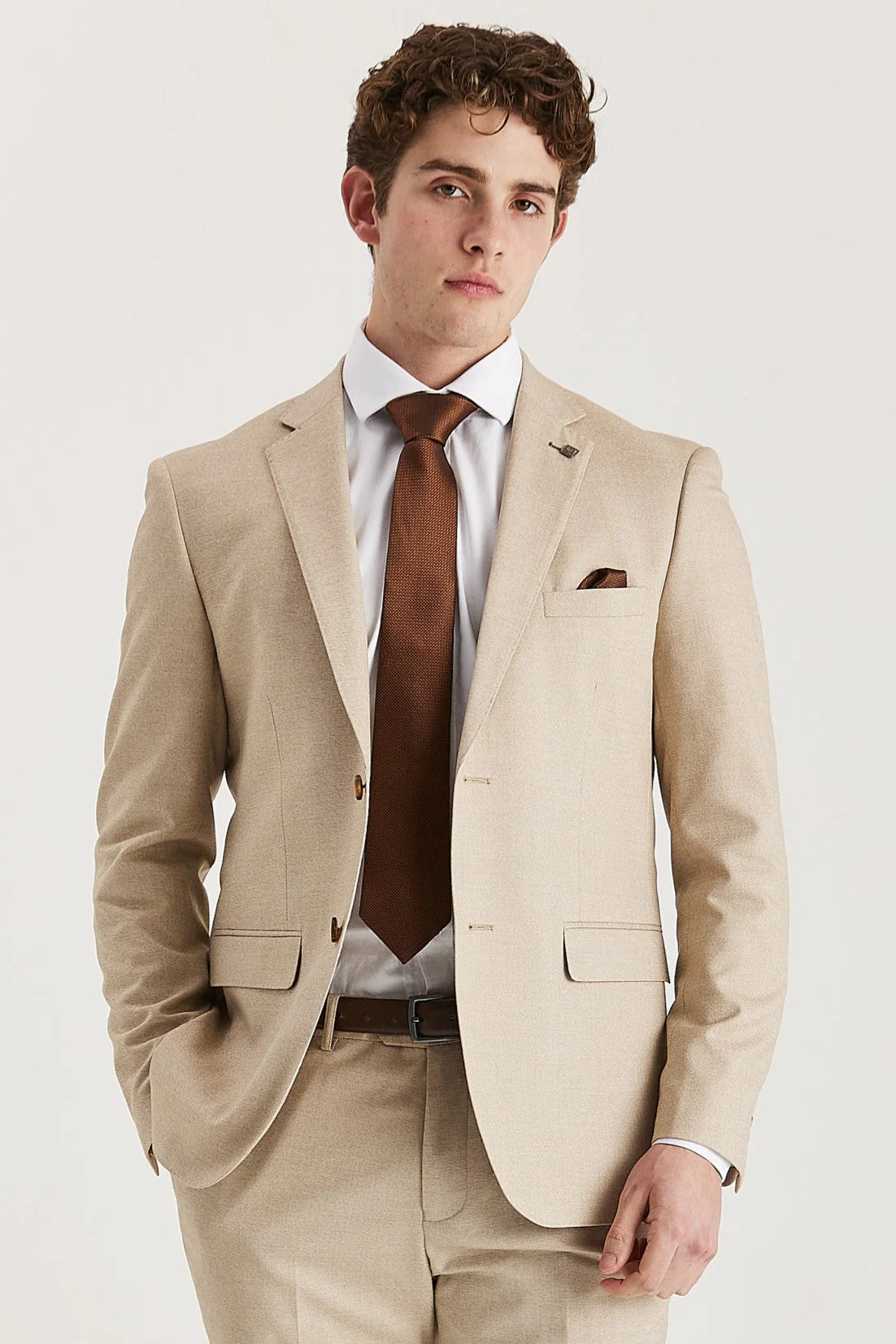 Waist-up front view of a man wearing the Belmont Beige Men's Two Piece Suit jacket, paired with a crisp white shirt, brown tie, and matching pocket square