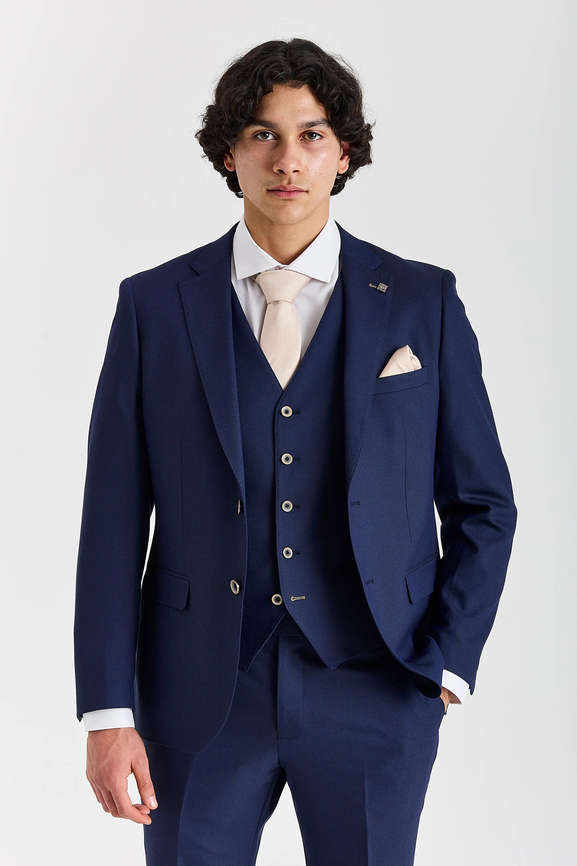 Front view of a man wearing a Belmont navy three piece suit with waistcoat, trousers, white shirt and cream tie.