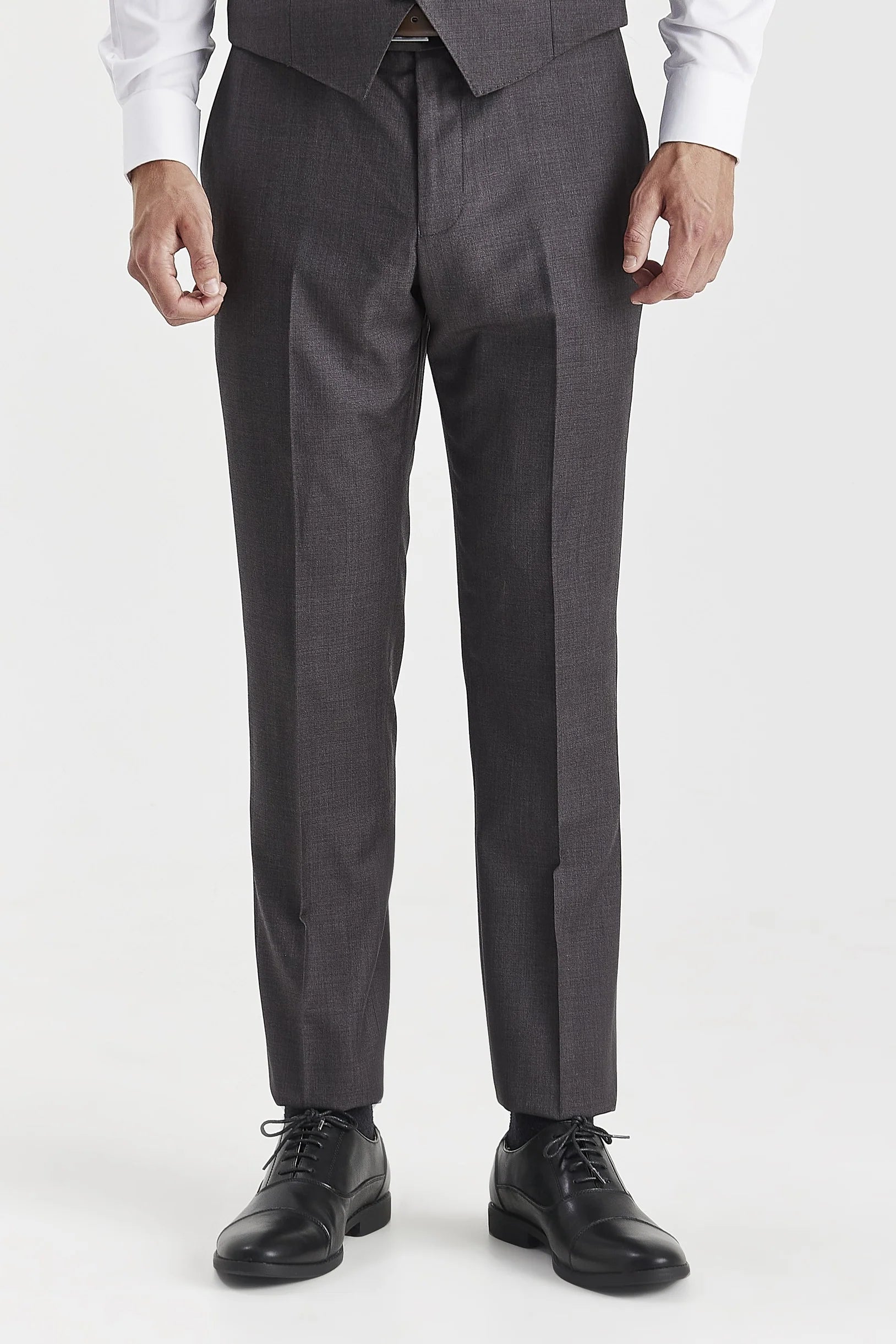 Front view of charcoal trousers, shown with a matching waistcoat, white shirt cuffs and black shoes.