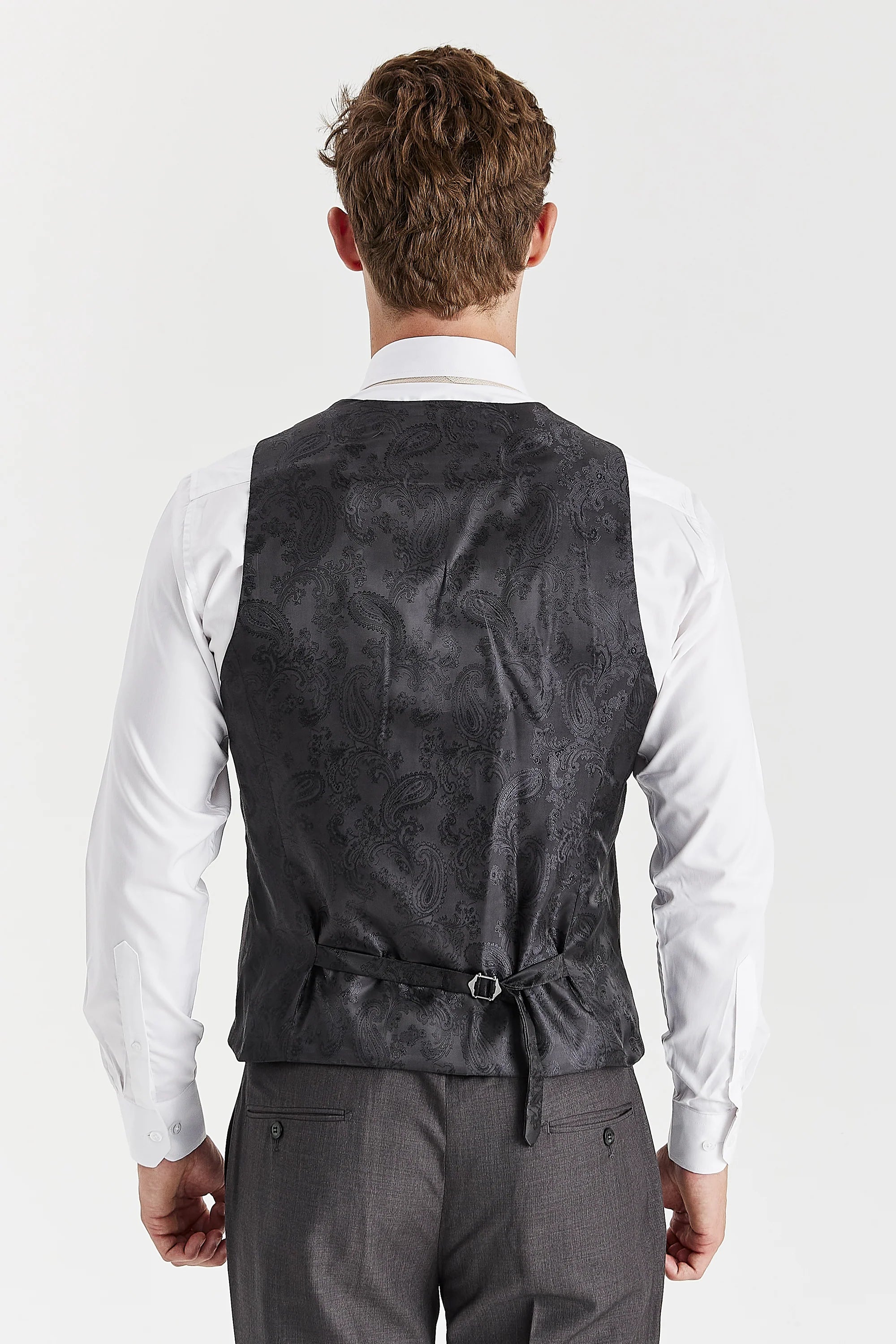 Rear view of the charcoal waistcoat with a black paisley back panel and adjustable strap, worn with a white shirt and matching trousers