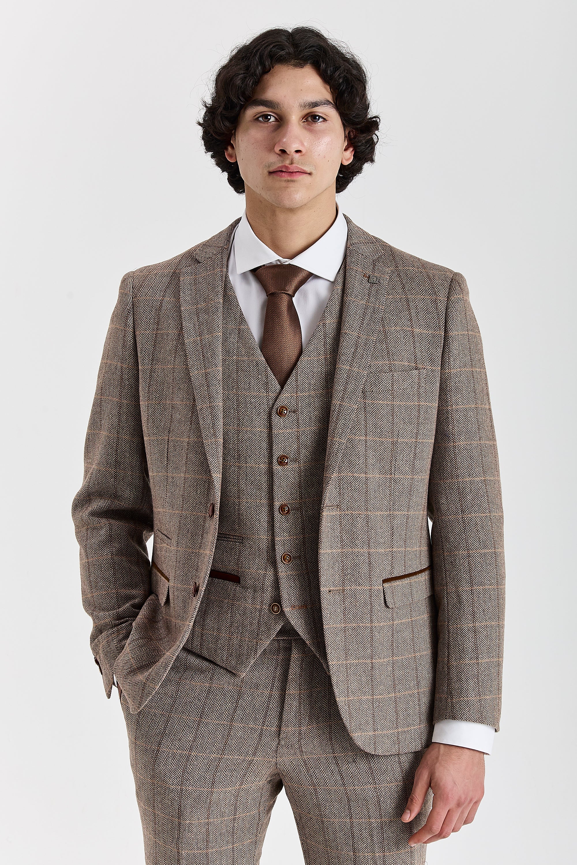 Front view of a man wearing a Harris brown herringbone tweed check three piece suit with waistcoat, trousers, white shirt and brown tie.