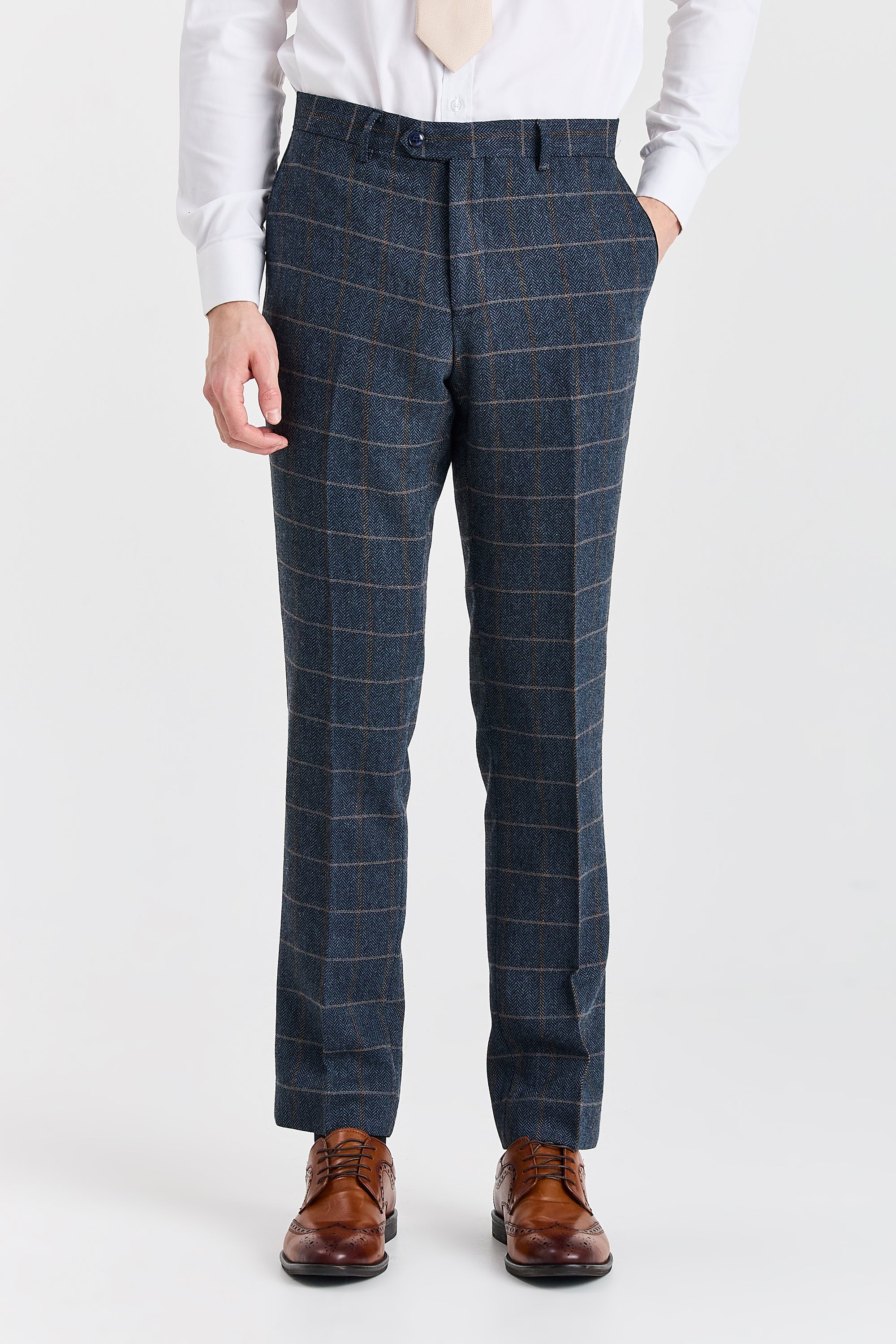 Front view of Harris navy herringbone tweed trousers with a tan windowpane check, worn with a white shirt and brown brogue shoes.