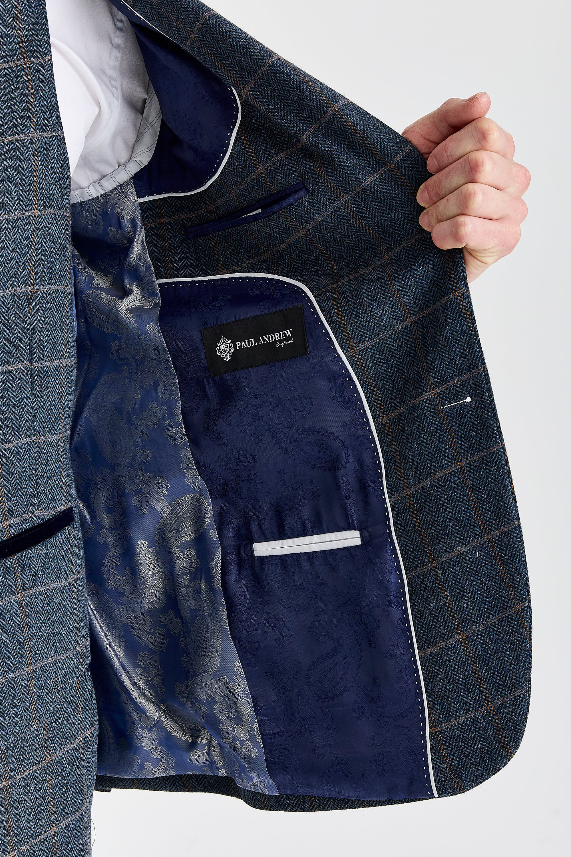 Detail view of a Harris navy herringbone tweed suit jacket with tan windowpane check, showing blue paisley lining, inner pocket and Paul Andrew label.