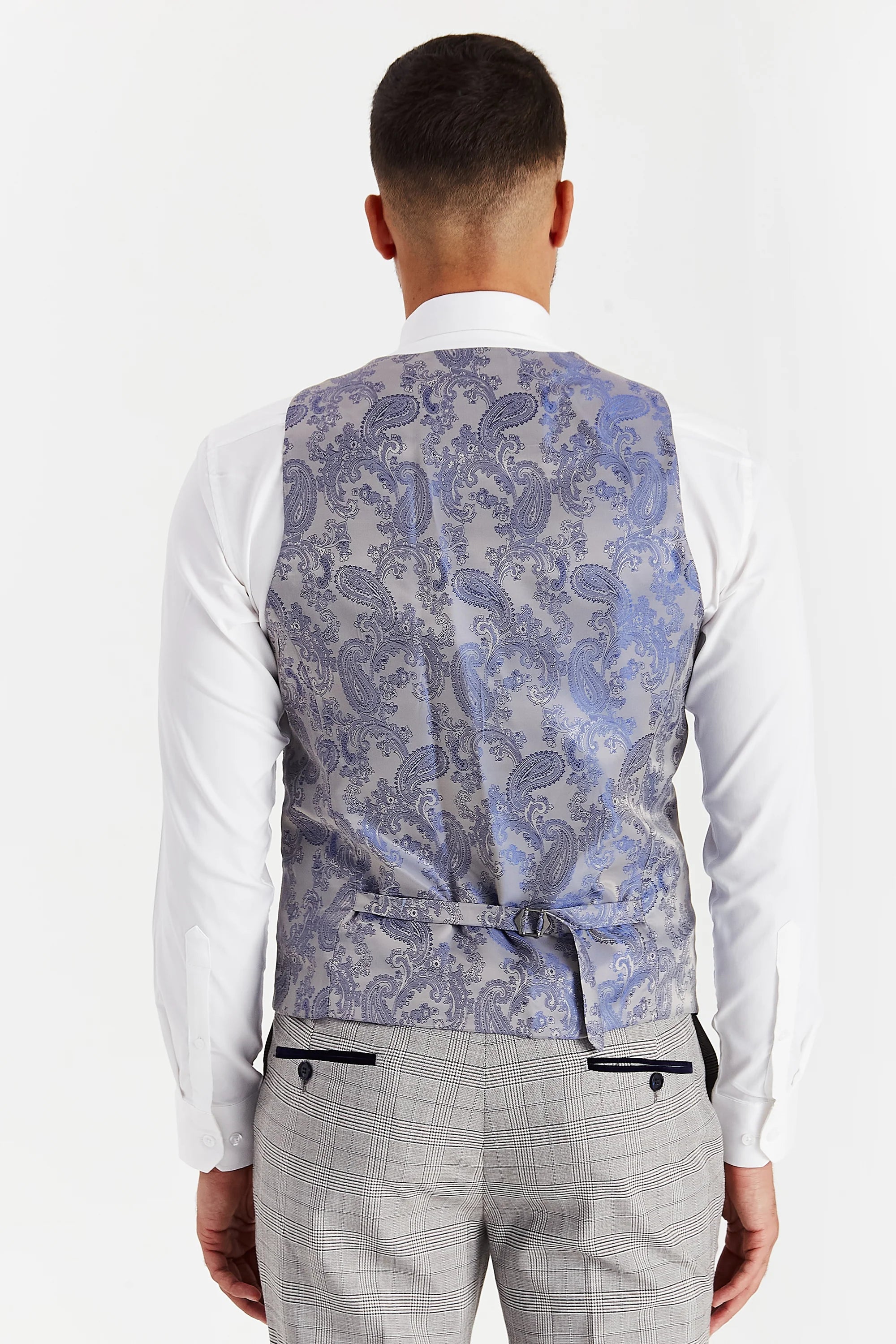 Rear view of the grey waistcoat with a silver paisley back panel and adjustable strap, worn with a white shirt and matching trousers.