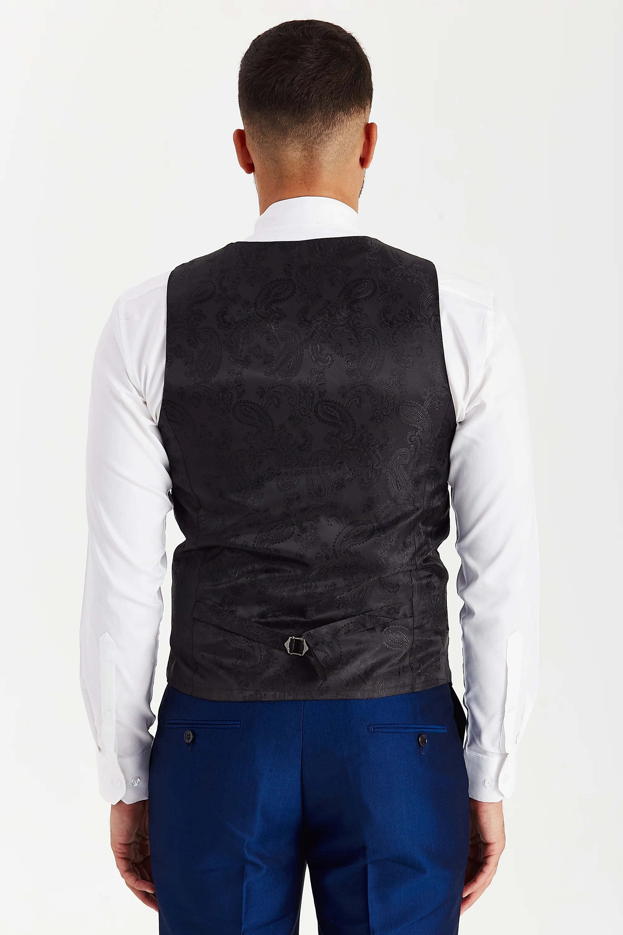 Rear view of the blue waistcoat with a black paisley back panel and adjustable strap, worn with a white shirt and matching trousers.
