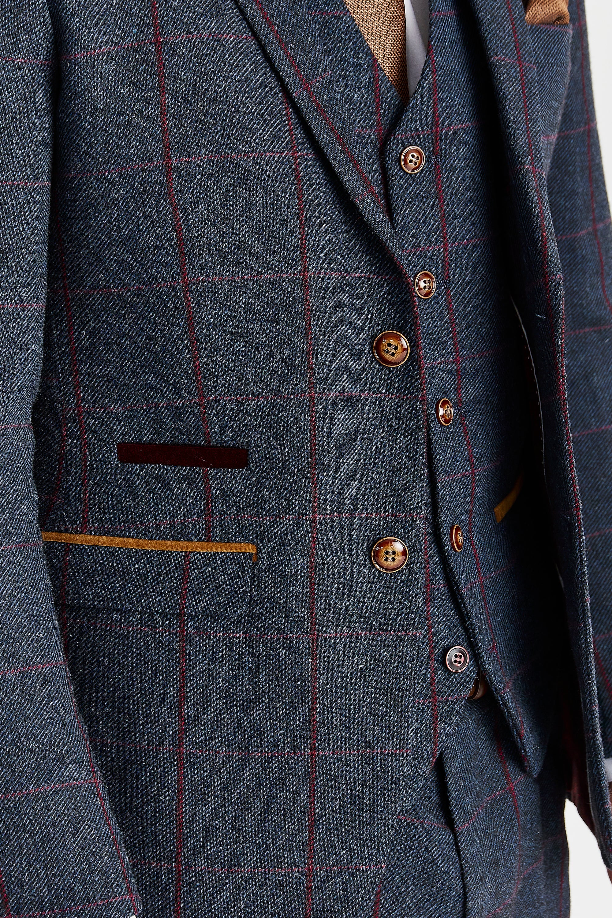 Detail view of navy tweed jacket and waistcoat fabric with a burgundy windowpane check pattern, brown buttons and tan pocket trim.
