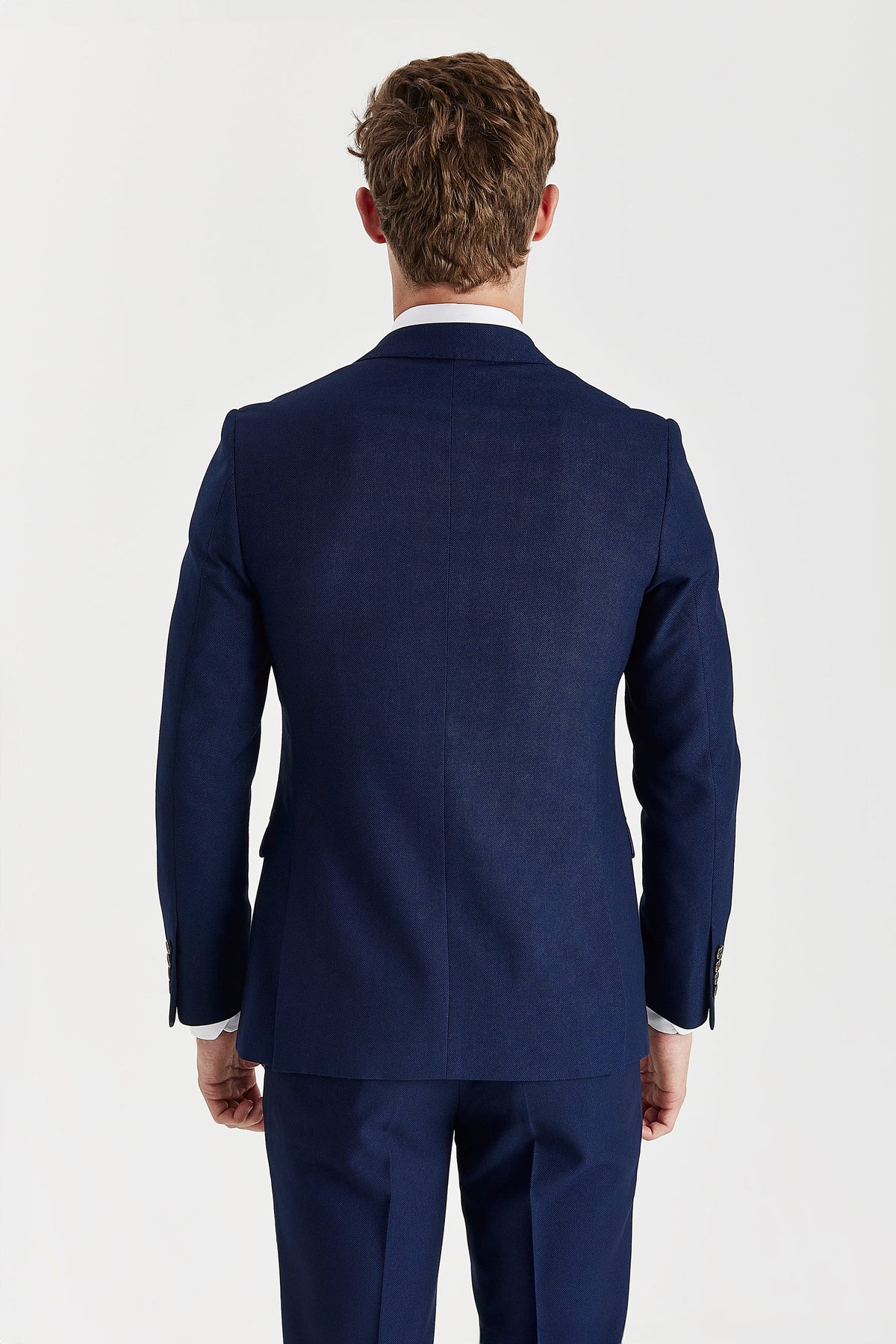 Rear view of the navy jacket showing its centre seam, shaped waist and twin back vents.