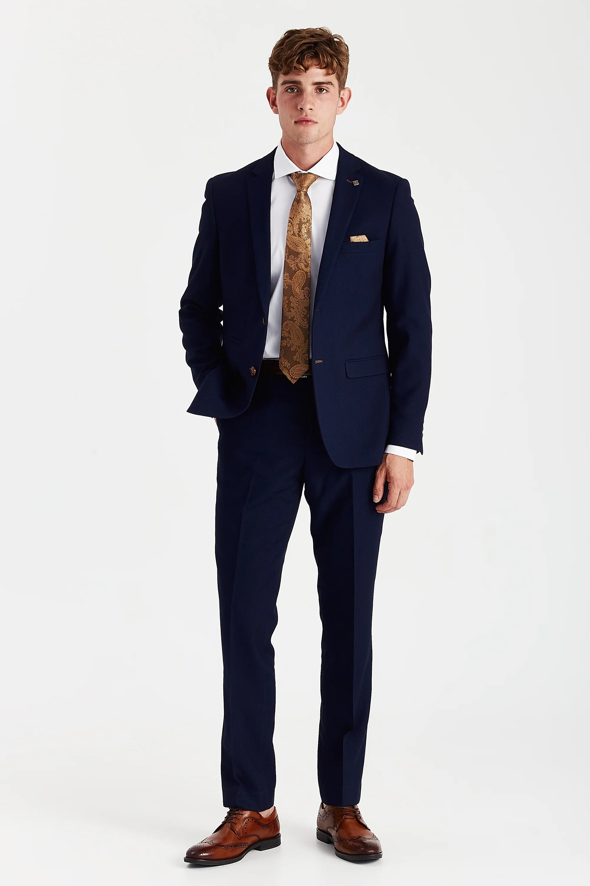 Full front view of navy textured two-piece suit worn with a white shirt, gold paisley tie and brown brogues
