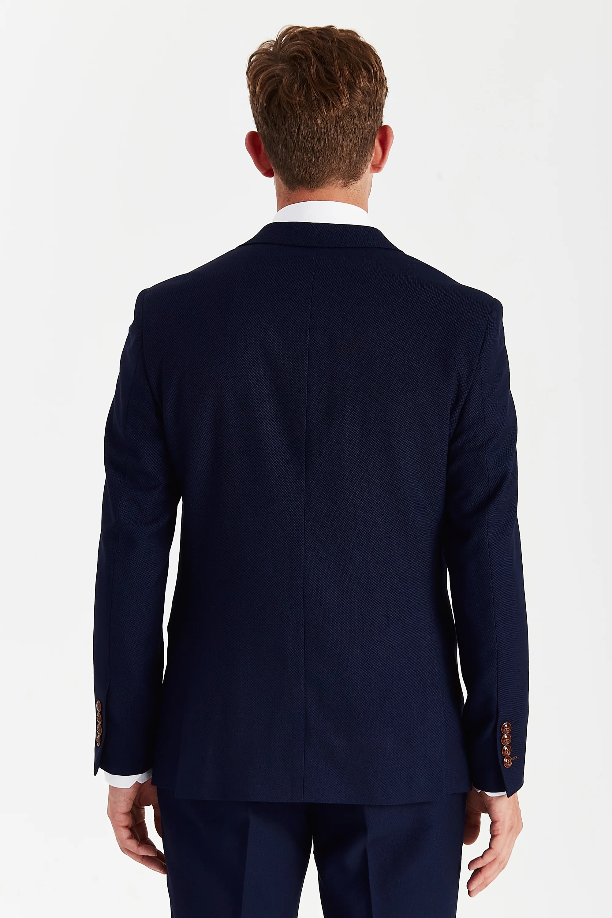 Back view of a navy textured suit jacket with matching trousers and brown sleeve buttons.