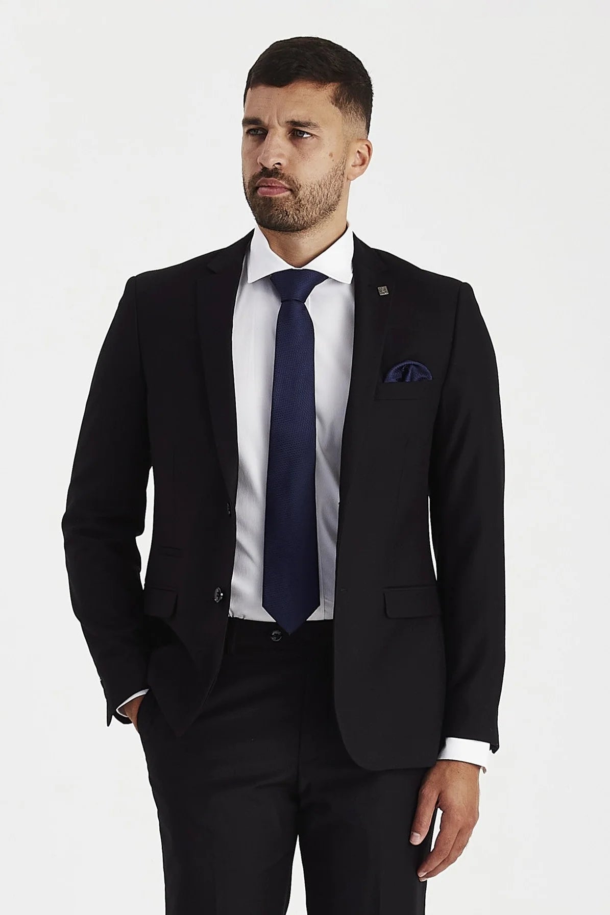 Half-body front view of a man modeling the Parker Men's Black Blazer, paired with a classic white shirt, navy blue tie, and matching navy pocket square.