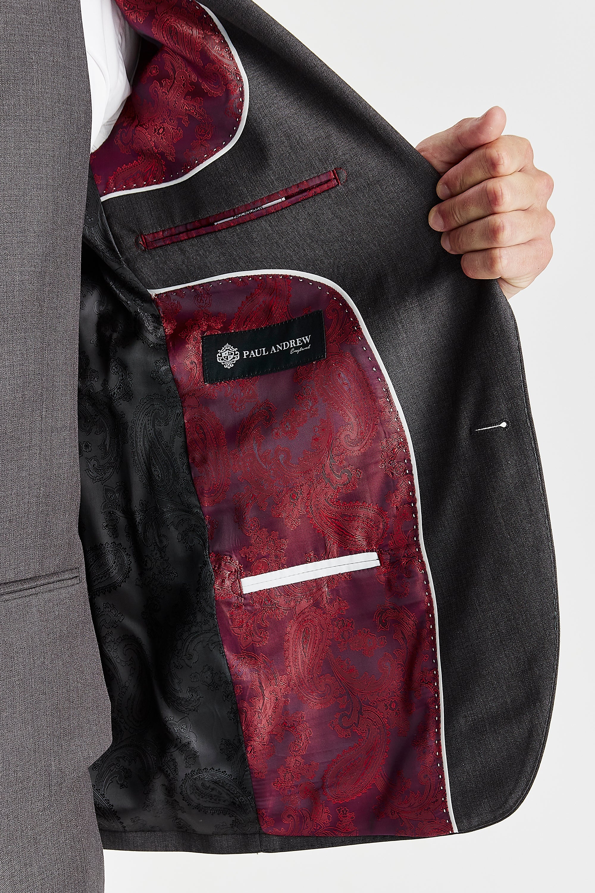 Interior view of the Charles charcoal blazer , showing the striking red and black paisley lining, a white-trimmed internal pocket, and the Paul Andrew brand label.