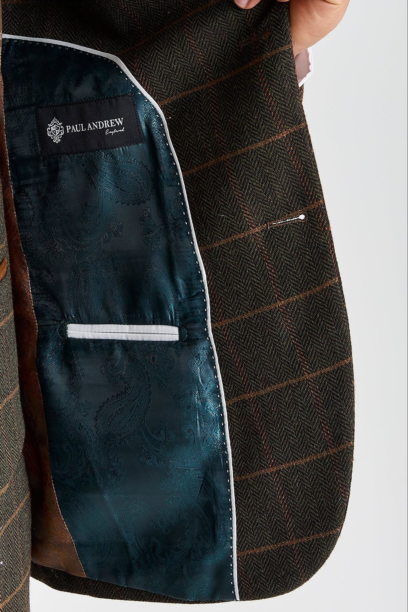 Interior view of green herringbone tweed check blazer with brown and green paisley lining and visible Paul Andrew logo label.