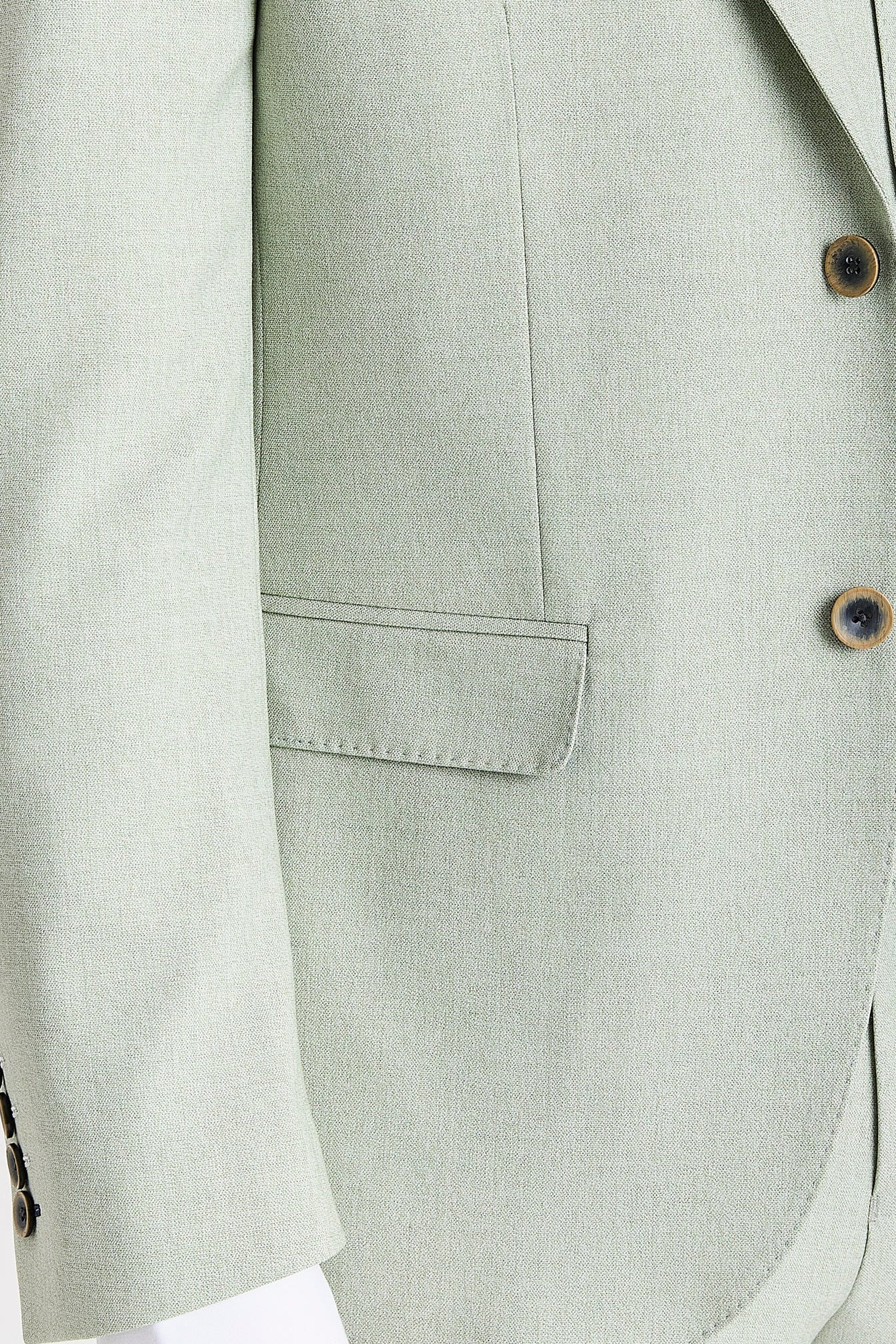 Close-up view of sage blazer with buttons and a front flap pocket.