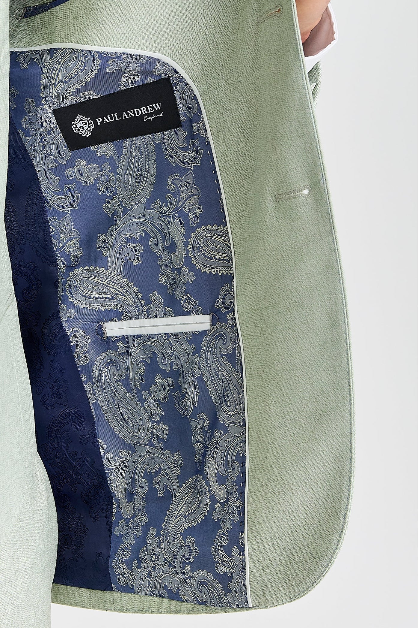 Interior view of sage blazer with silver and navy paisley lining and Paul Andrew logo branding.