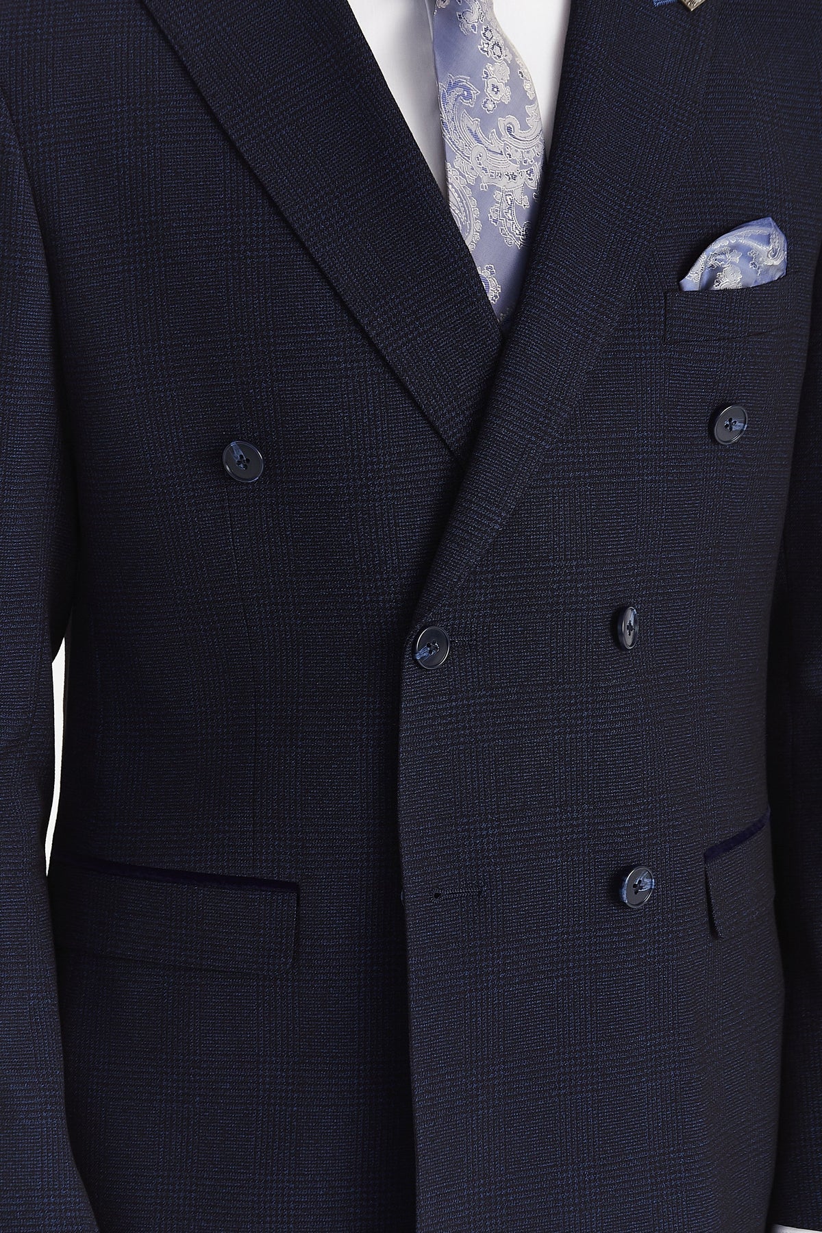 Close-up of the jacket’s fine navy check pattern, overlapping front, blue buttons and navy suede trim above the flap pockets.