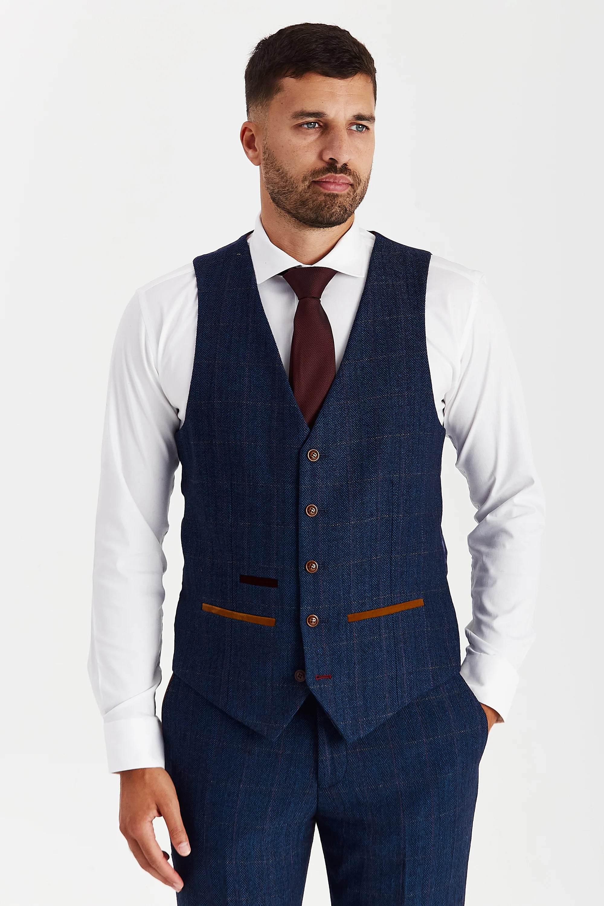 Front view of the navy tweed waistcoat with brown buttons and suede pocket trimmings, worn with matching trousers, a white shirt and a burgundy tie.