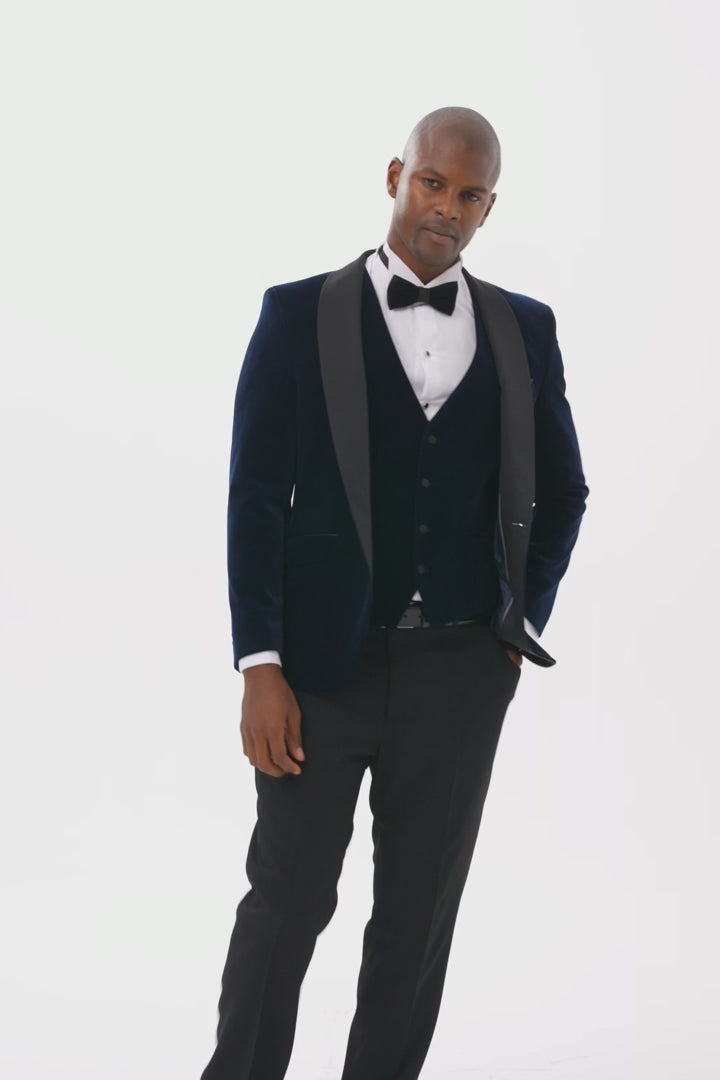 Model wearing midnight blue velvet dinner jacket and waistcoat with black satin shawl lapels video where the model is turning around and then showing inside lining brand and then front angle view of top half of the jacket.