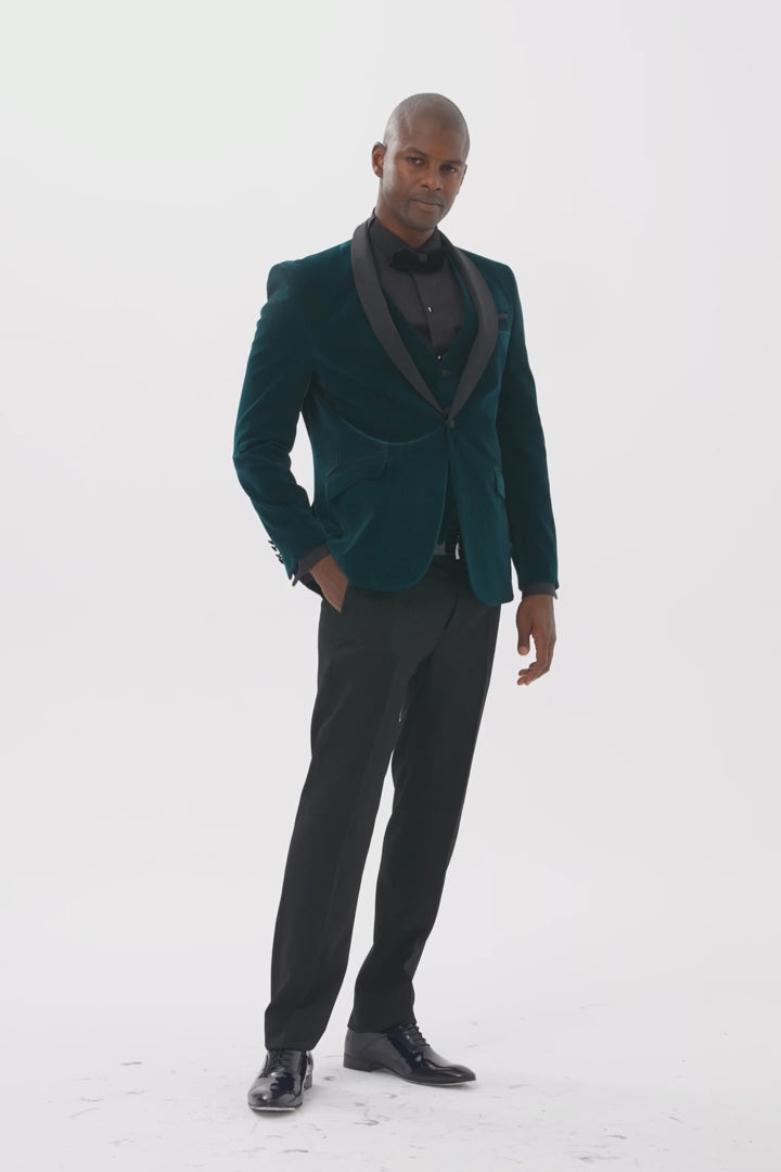 Model wearing emerald green velvet dinner jacket and waistcoat with black satin shawl lapels, walking towards the camera