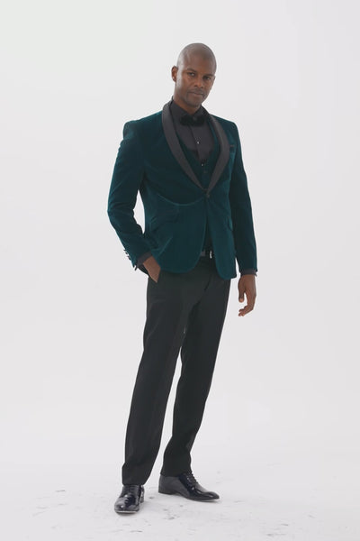 Model wearing emerald green velvet dinner jacket and waistcoat with black satin shawl lapels, walking towards the camera