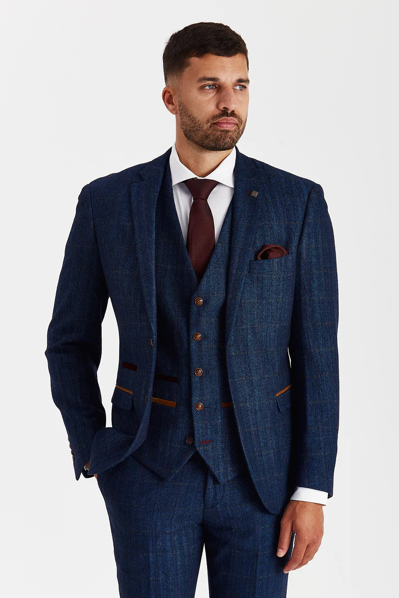 closer view of a man in a navy tweed check three piece suit, highlighting the jacket and waistcoat detailing, with the burgundy tie adding contrast against the textured fabric
