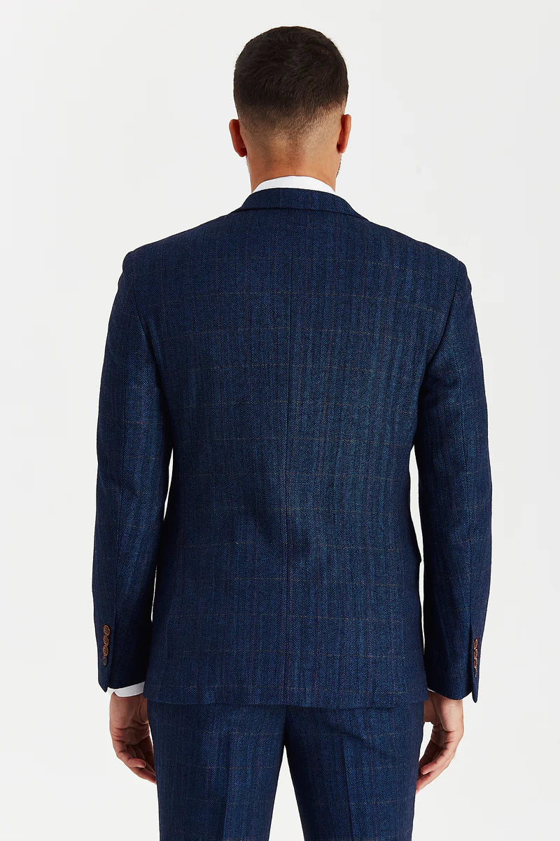 back view of a man wearing a navy tweed check suit jacket and matching trousers, showing the clean tailored lines and the texture of the tweed fabric
