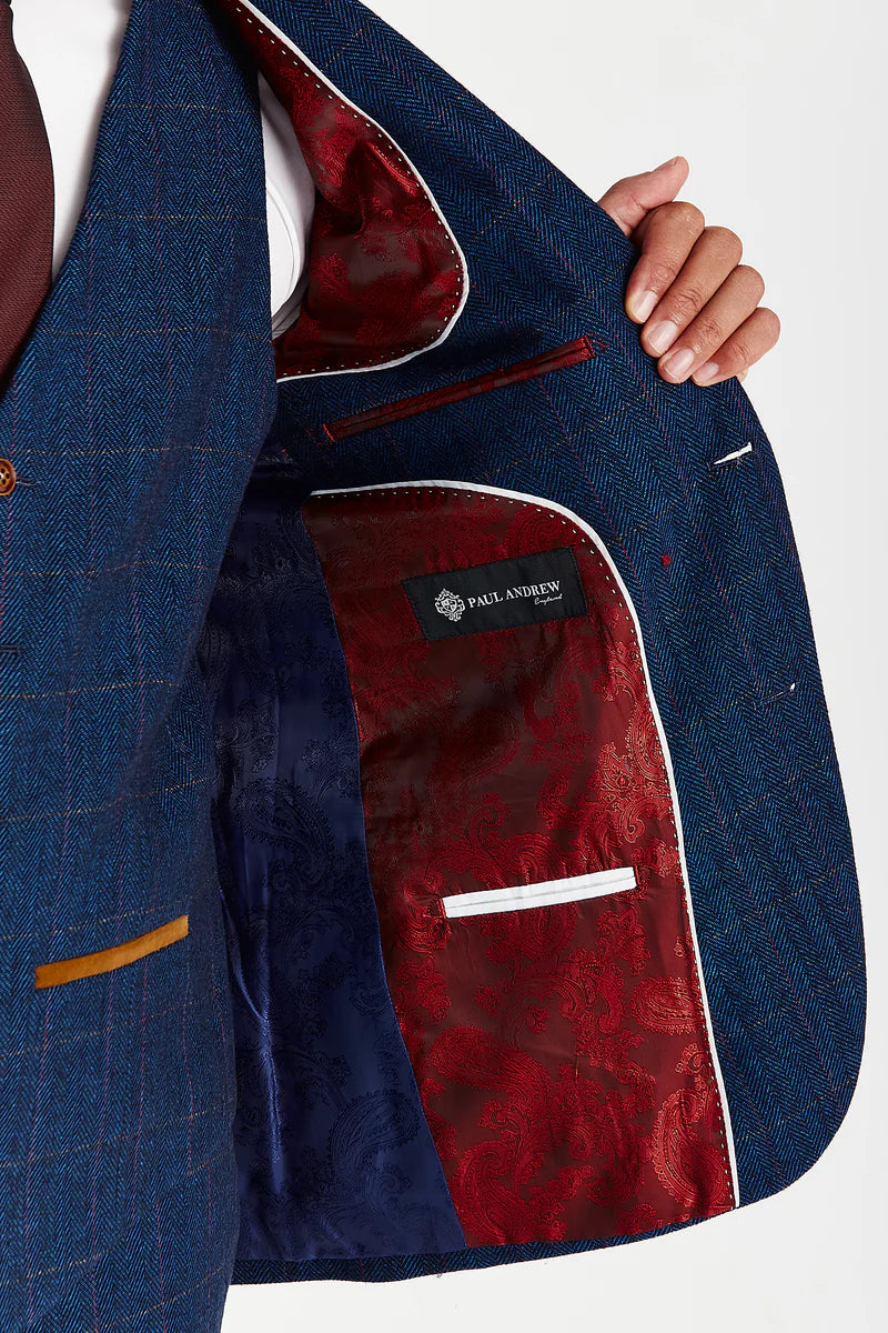 open view of the suit jacket revealing a rich red paisley lining with white piping, shown while the man holds the jacket open to display the inner craftsmanship and the Paul Andrew Logo