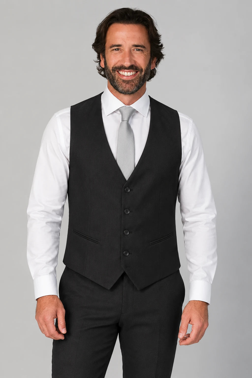 Front view of black Thomas Goodwin waistcoat with four buttons, two welt pockets, worn over a white shirt.